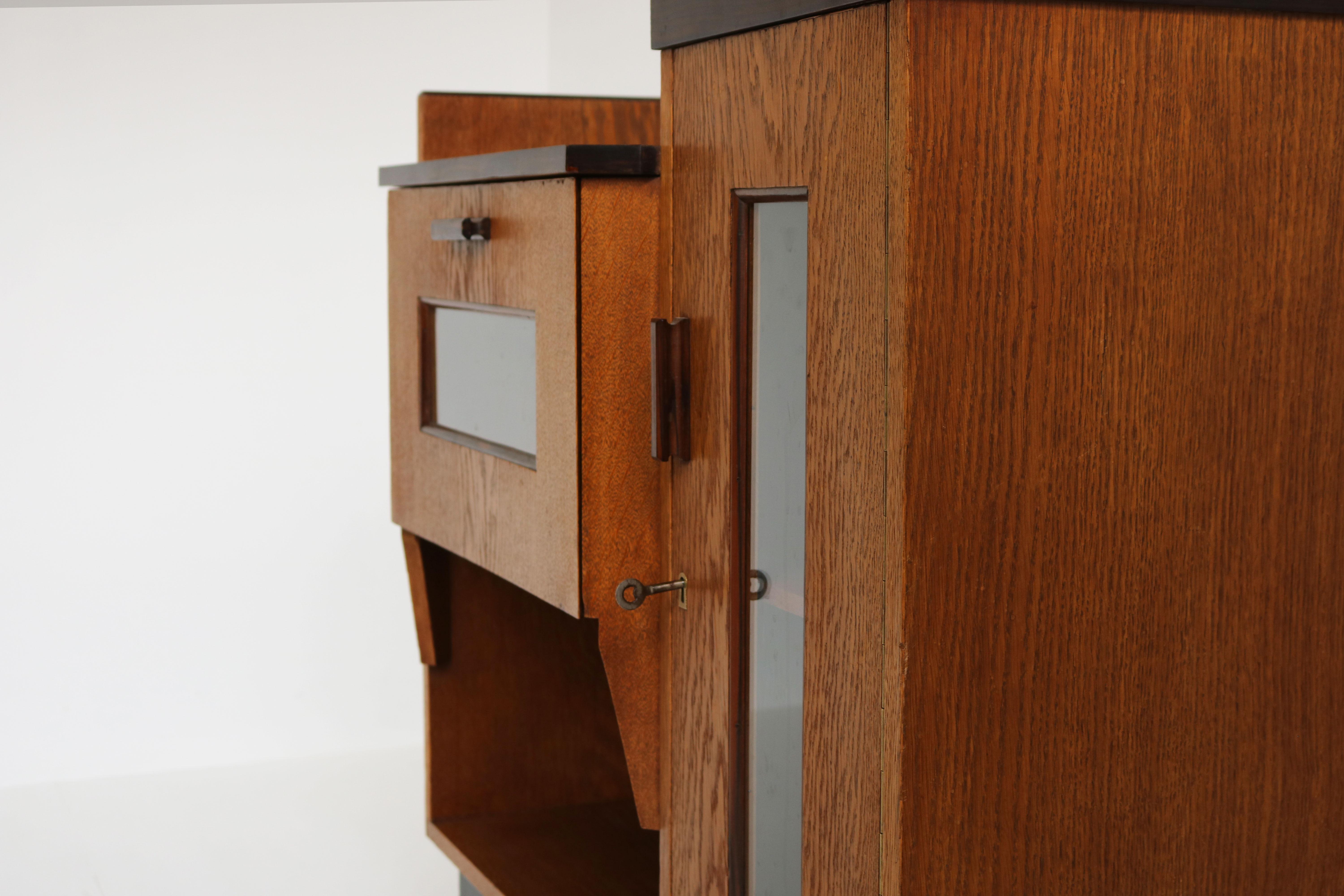 Stunning & clean! This 1920 Dutch Art Deco design Tea cabinet / sideboard by P.E.L Izeren for Genneper Molen furniture factory in Amsterdam School Design style. 
Exquisite square Art Deco shapes with European Oak an ebonized base &