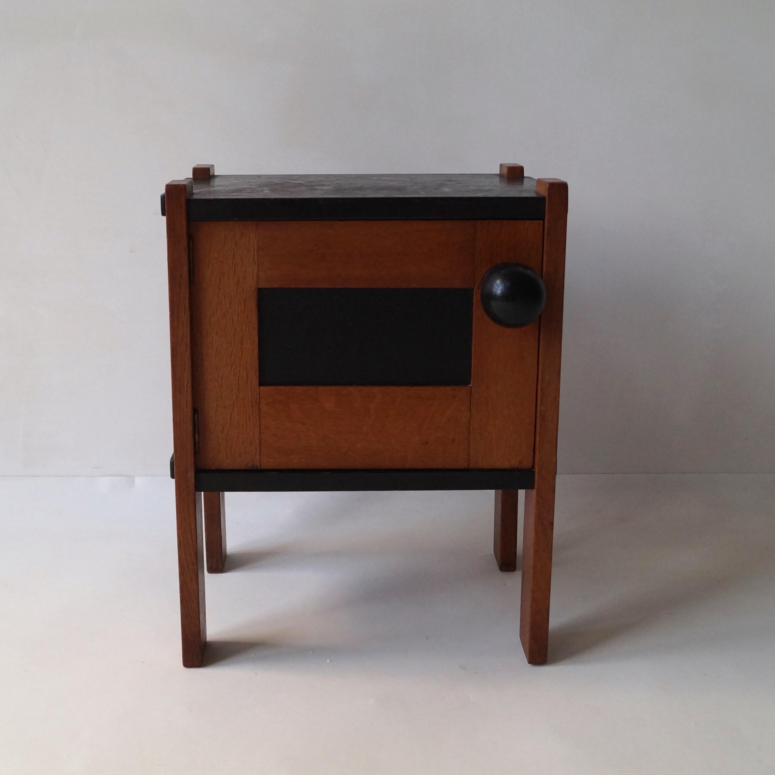 A lovely proportioned small Haagse School 1920s nightstand/cupboard by famous Dutch interior designer Cor Alons. It's executed in solid high quality oak, has a blackened panel on the door and an oversized door knob (where the early work of Alons is