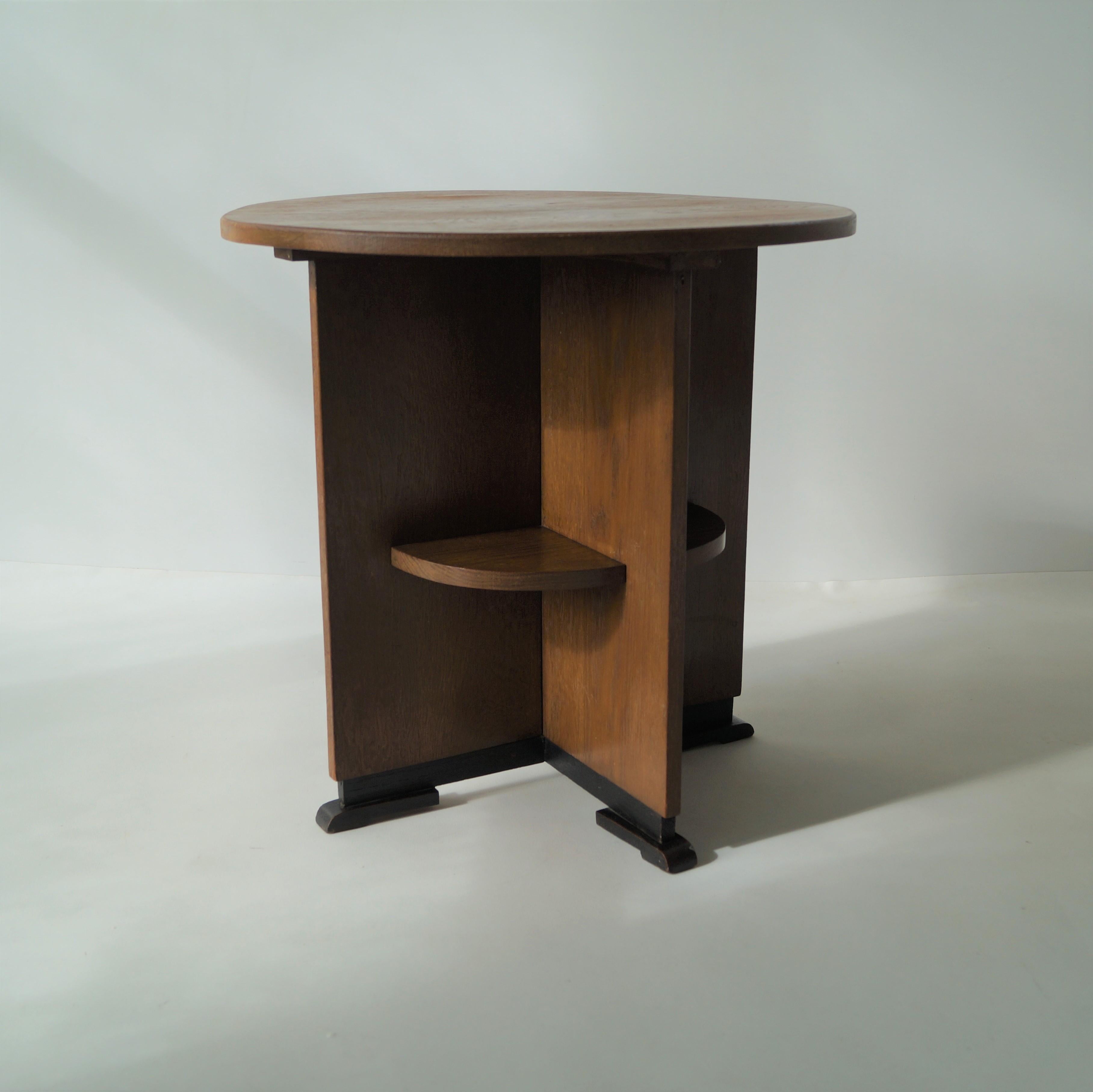 Dutch Art Deco modernist/Haagse School side table, in solid oak and a characteristic design. The table was made around 1920 in the Netherlands.
The base is symmetrically divided into 4 compartments, within each a shelve. The black leg ends look like