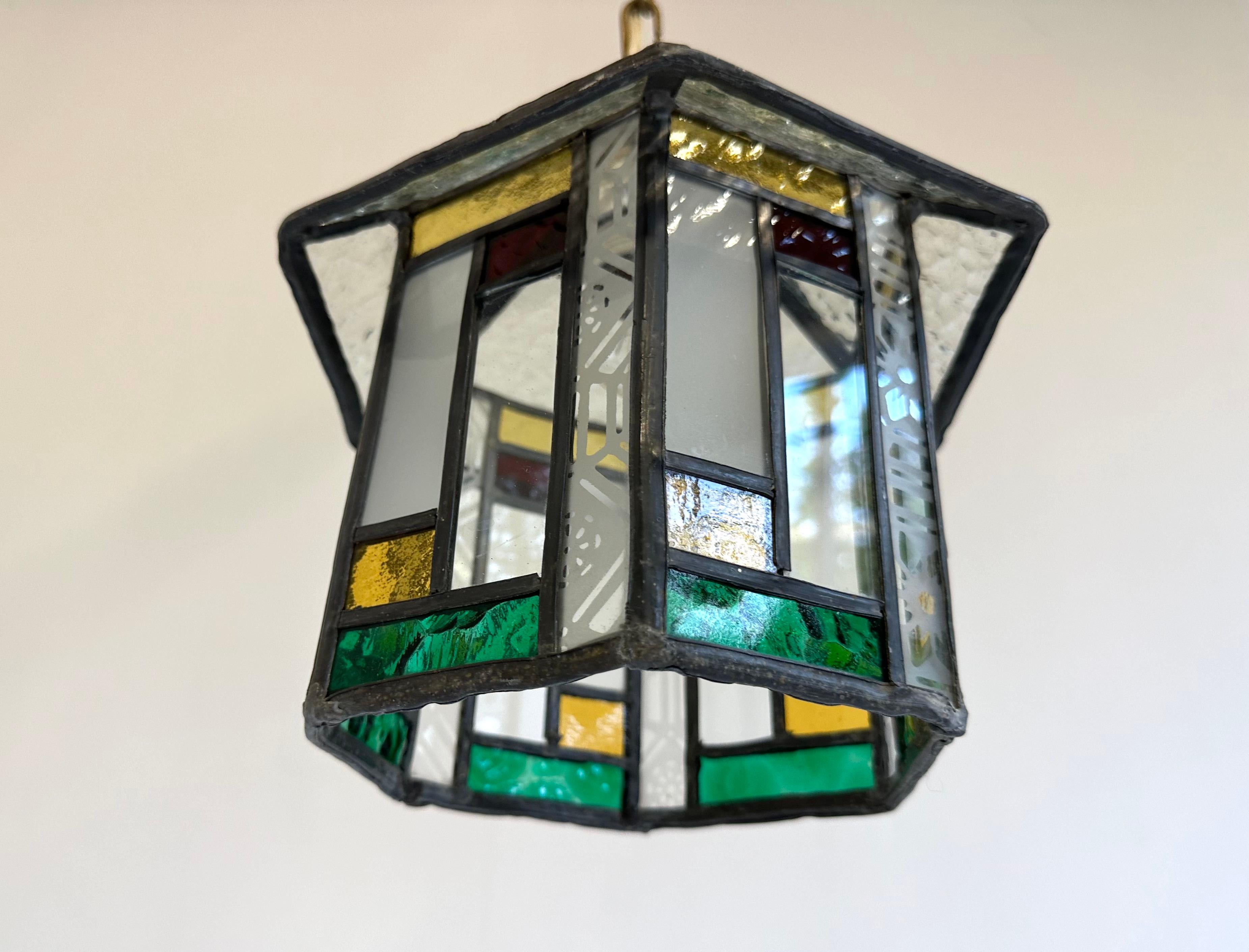 Introducing the strikingly beautiful 1920 Stained Glass Hallway Lantern. This Dutch Art Deco style lantern is the perfect addition to any home that appreciates the beauty of handcrafted glass. With brilliant jewel-toned hues and intricate geometric
