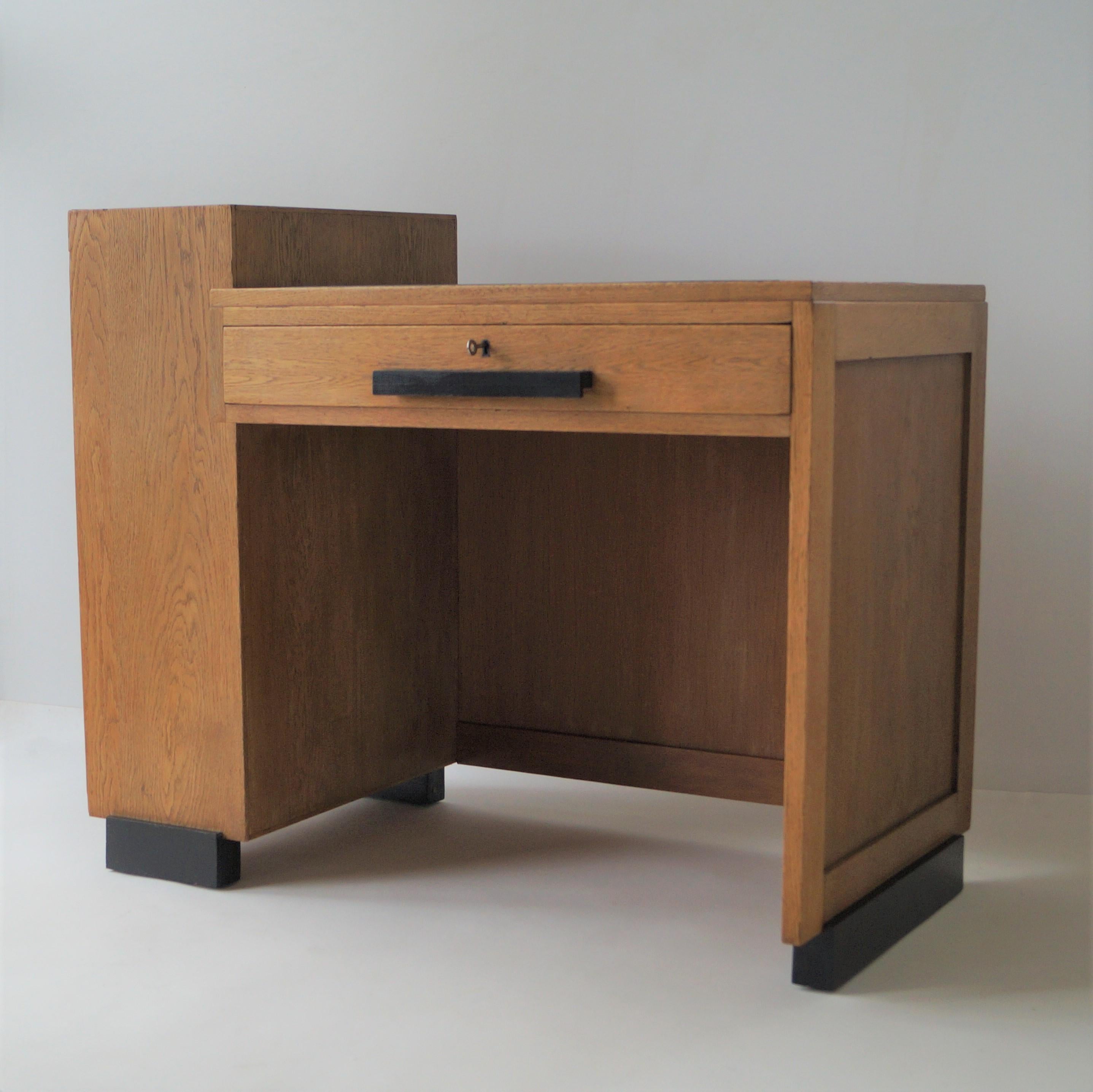 A modernist writing desk with an assymetrical design, Haagse School/modernist piece,

It has one large drawer at the front and a three shelves storage compartment at the left. On the desktop a black leather inlay. The desk was manufactured by Fa.