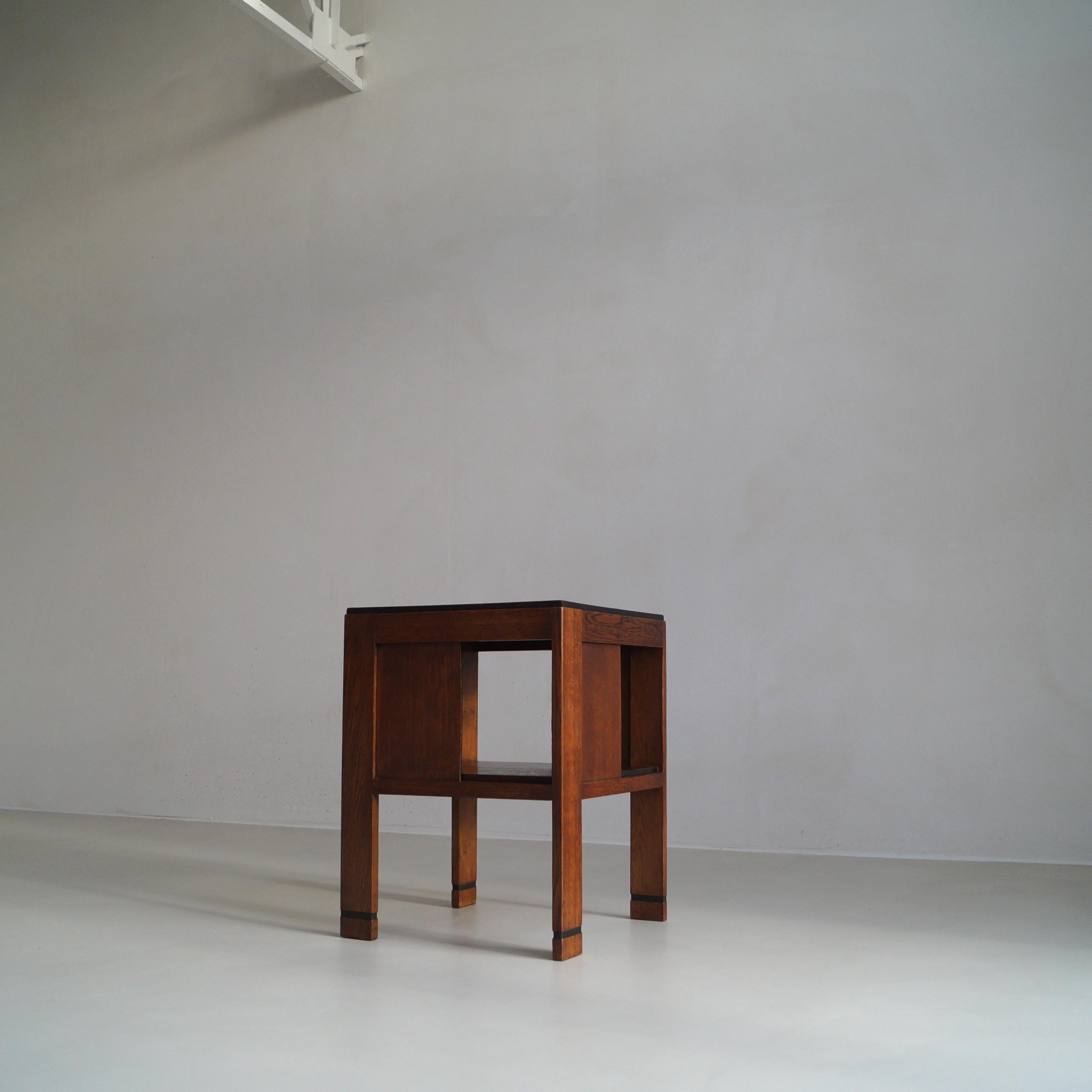 A two tiered side table or occasional table, 1920s, with a modernist design. Each tableleg is is a quarter turned relative to the next. The piece is made of oak, and has black stained details around tabletop and on the lower half of the tablelegs.