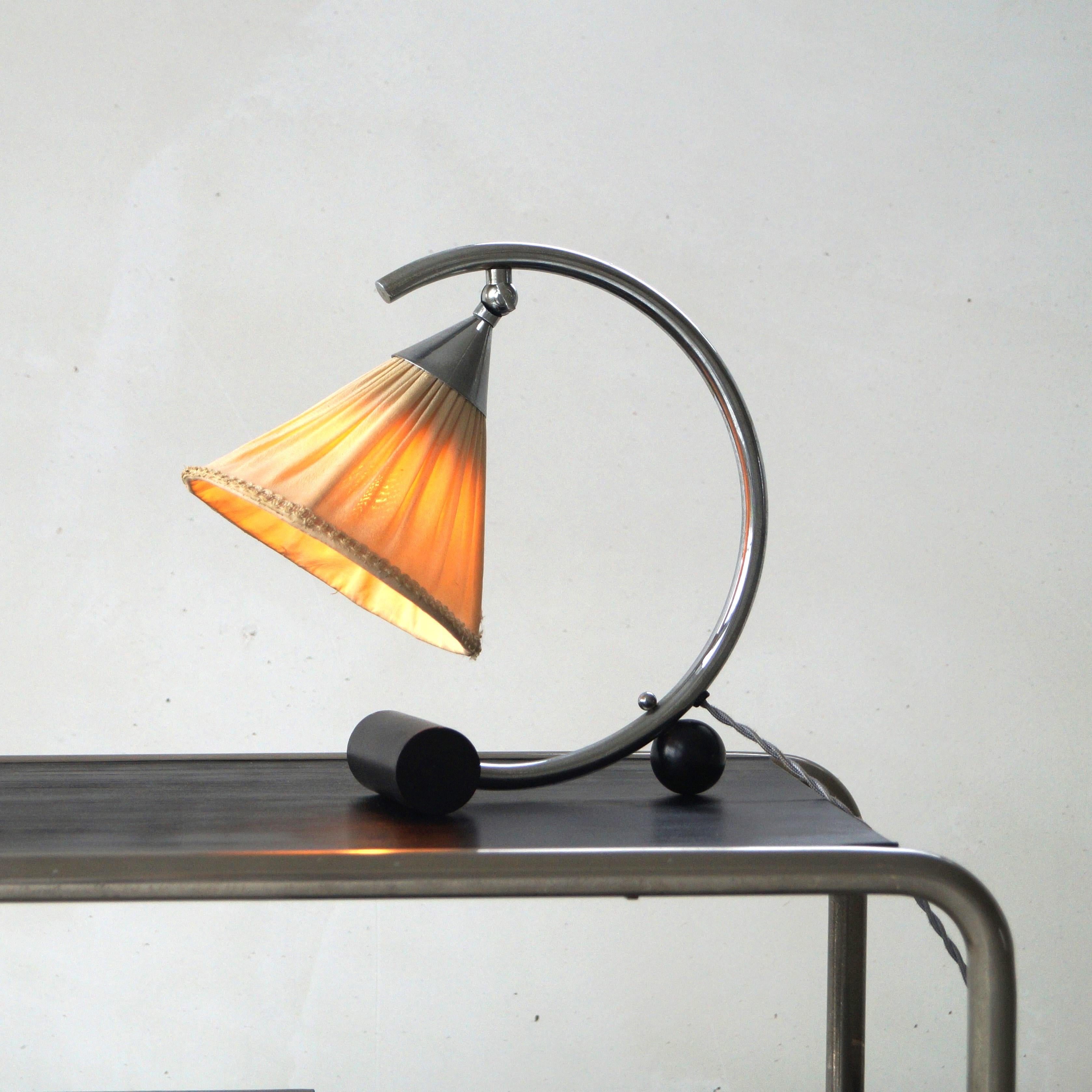 A rare 1930s modernist table lamp or bedside lamp with an extraordinary design and its original lampshade which is in fair condition regarding its age. Ideal to be used as a bedside lamp or as a decorative piece on a bookshelf or sideboard. Pairs