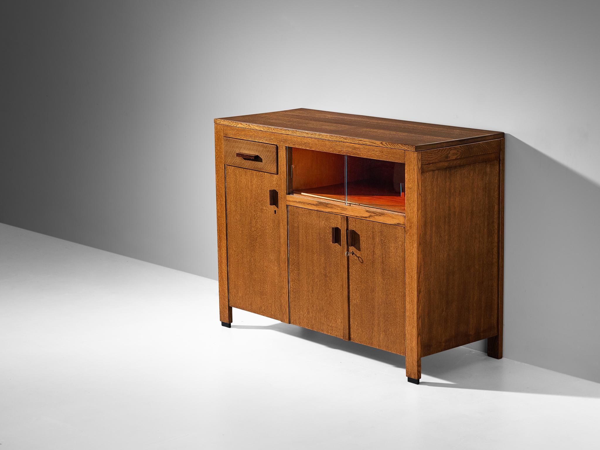 Sideboard, oak, coromandel, glass, The Netherlands, 1930s

Elegant Amsterdamse School sideboard with a modest design defined by characteristic elements that impart the piece with a unique appearance. The sideboard is equipped with three asymmetrical