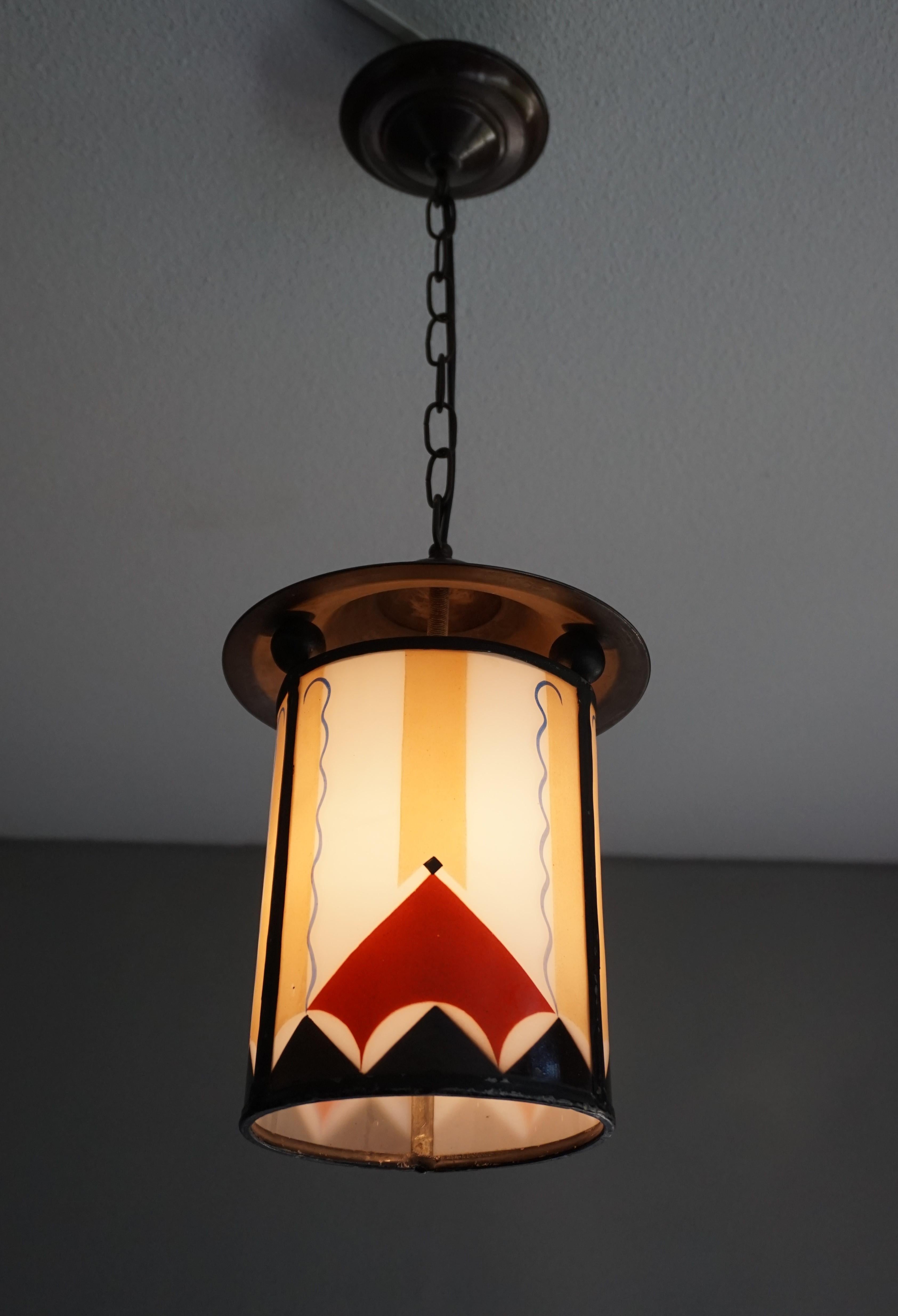 Handcrafted lantern-like pendant from the early 1900s.

This rare and highly stylish fixture was made in early 20th century Amsterdam. The colors of the hand and spray painted geometrical patterns on the rounded, milky glass panels make this work of