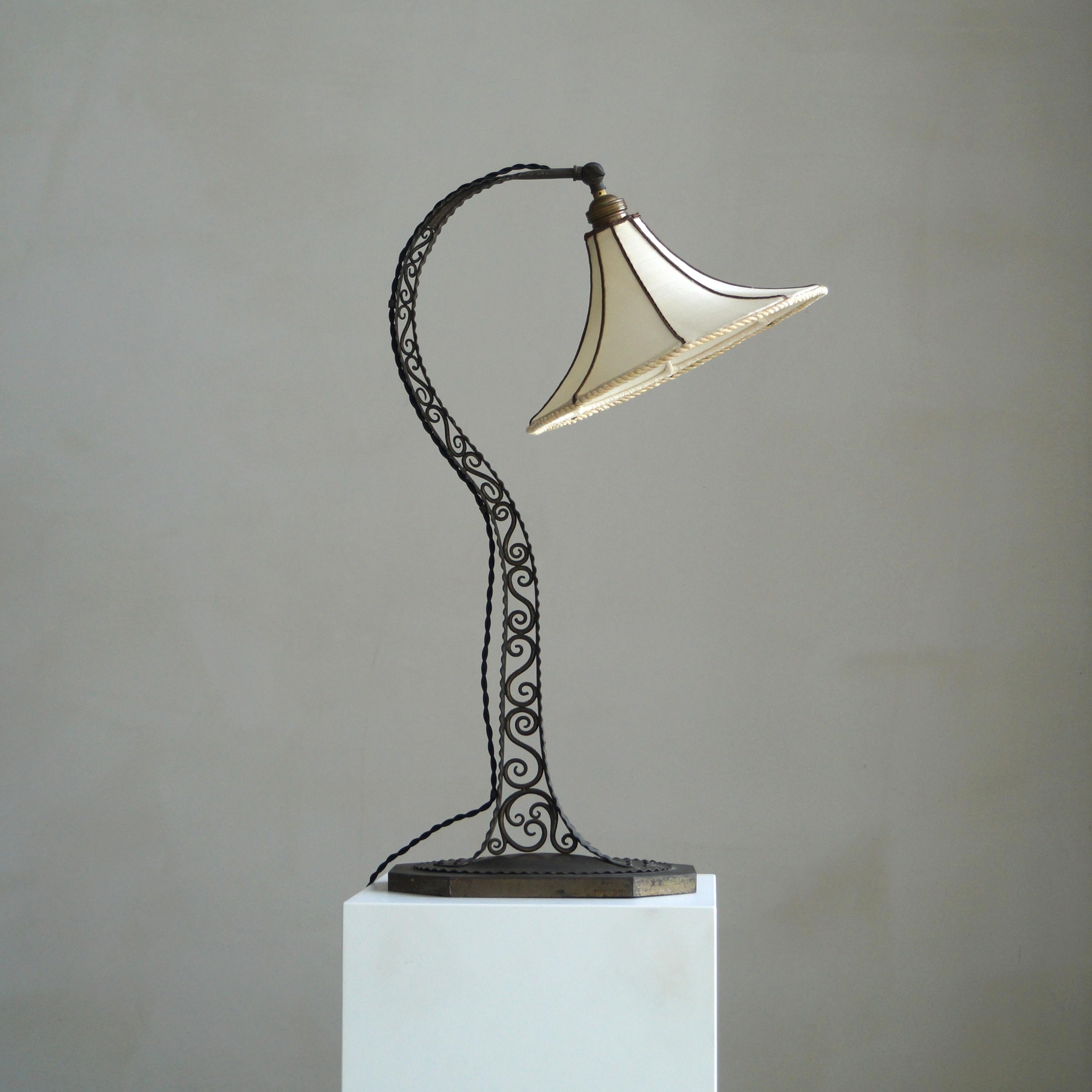 Eine elegante und große antike Tischlampe aus den 1920er Jahren, die den dekorativen Geist der Amsterdamer Schule/Arts & Crafts-Periode wunderbar verkörpert.
Der Sockel und der Stiel aus patiniertem Kupfer sind mit handgeschmiedeten Schnörkeln und