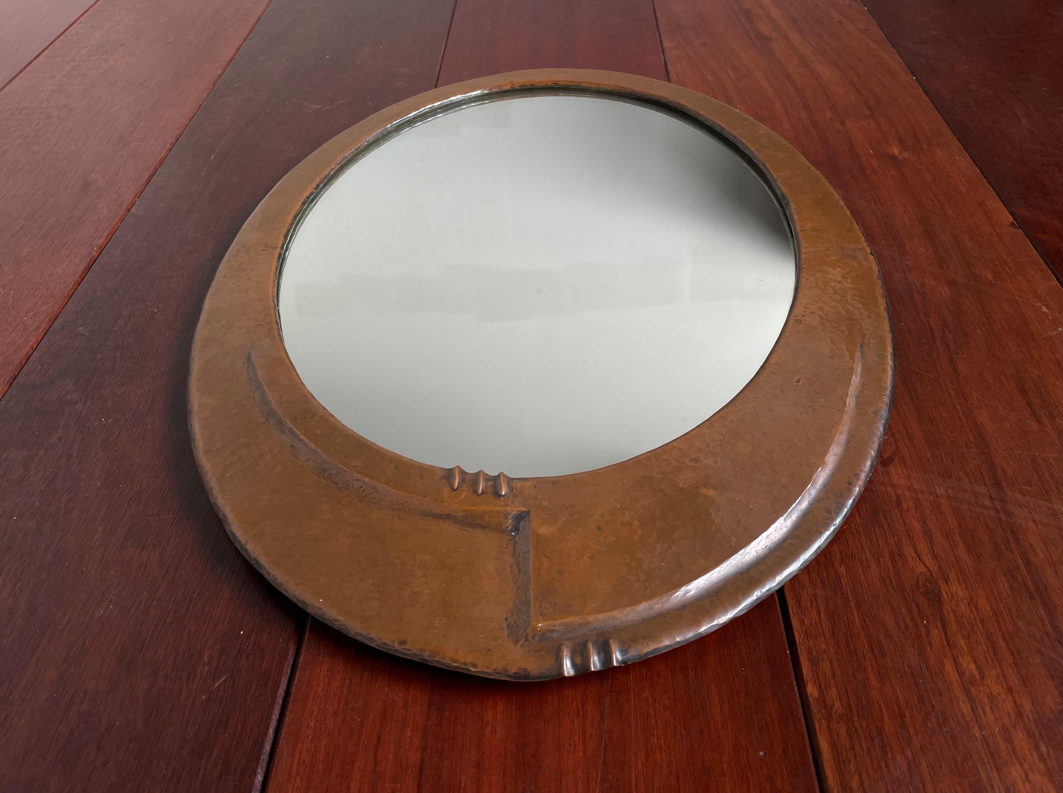 Early 1900s artistic design Arts & Crafts wall mirror.

This all-handcrafted, practical size Arts & Crafts antique with its original mirror is an absolute joy to own and look at. The unusual and attractive asymmetrical design of the embossed