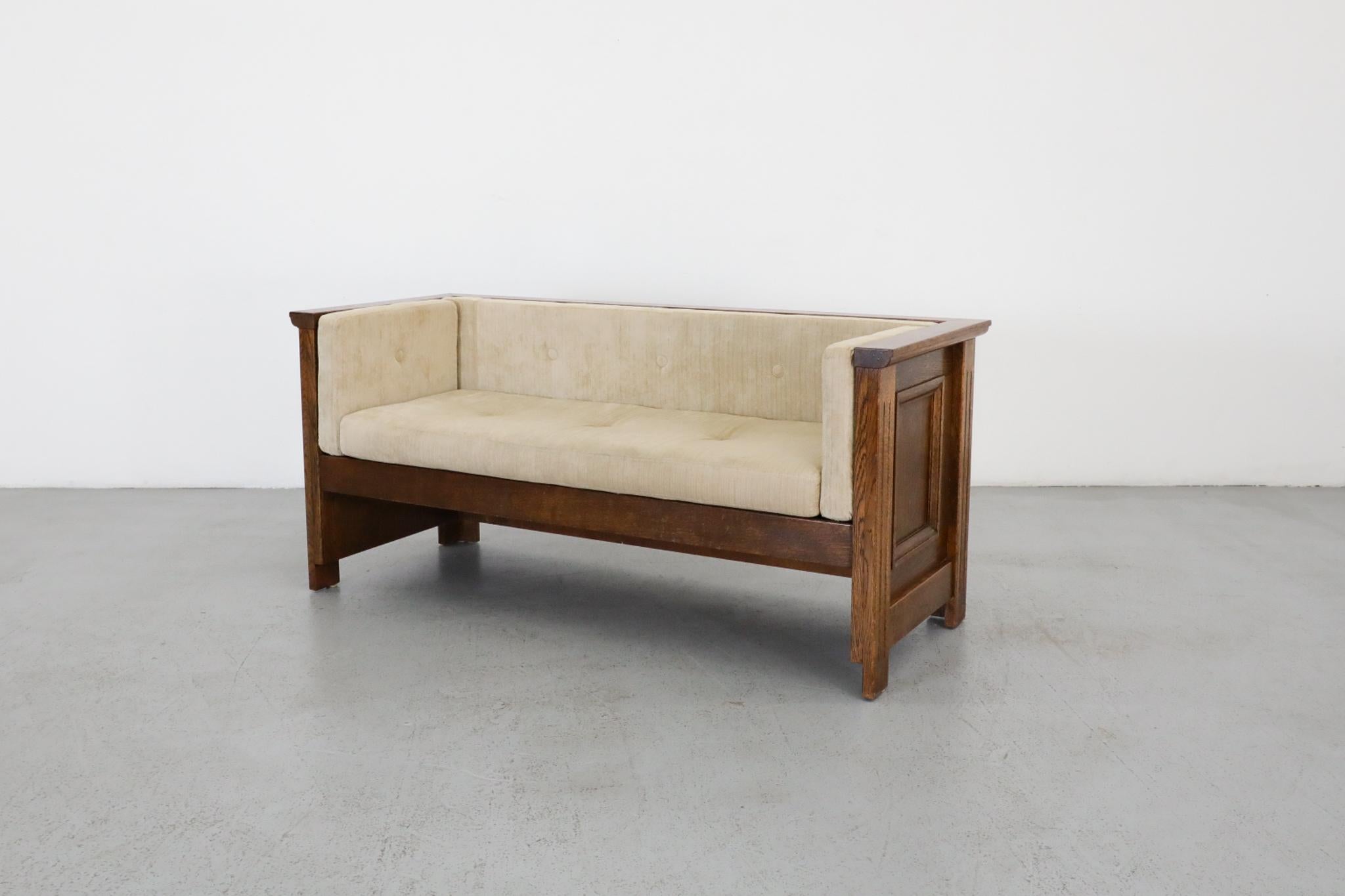 Un autentico divano o poltrona da sala in stile Arts and Crafts olandese, originario dei Paesi Bassi. Realizzato in robusto legno di quercia con i suoi cuscini originali color crema, questo pezzo esemplifica la dedizione del movimento a materiali