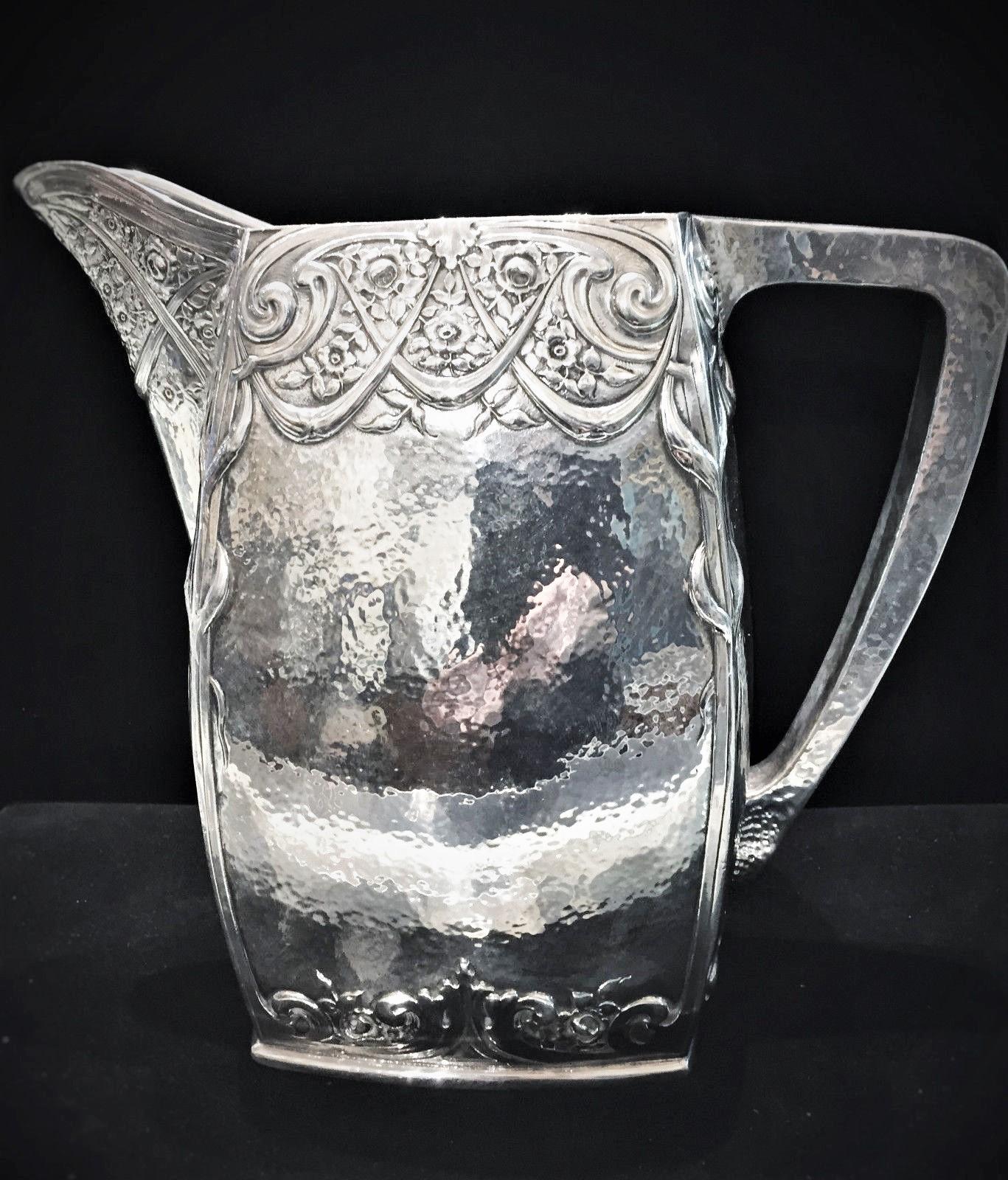 Probably Dutch. Lavishly designed in the style of Arts & Crafts / Art Nouveau, this outstanding handmade, hammered silver plated water pitcher was obviously crafted by a highly skilled silversmith. The hallmark on the bottom looks like a mill,