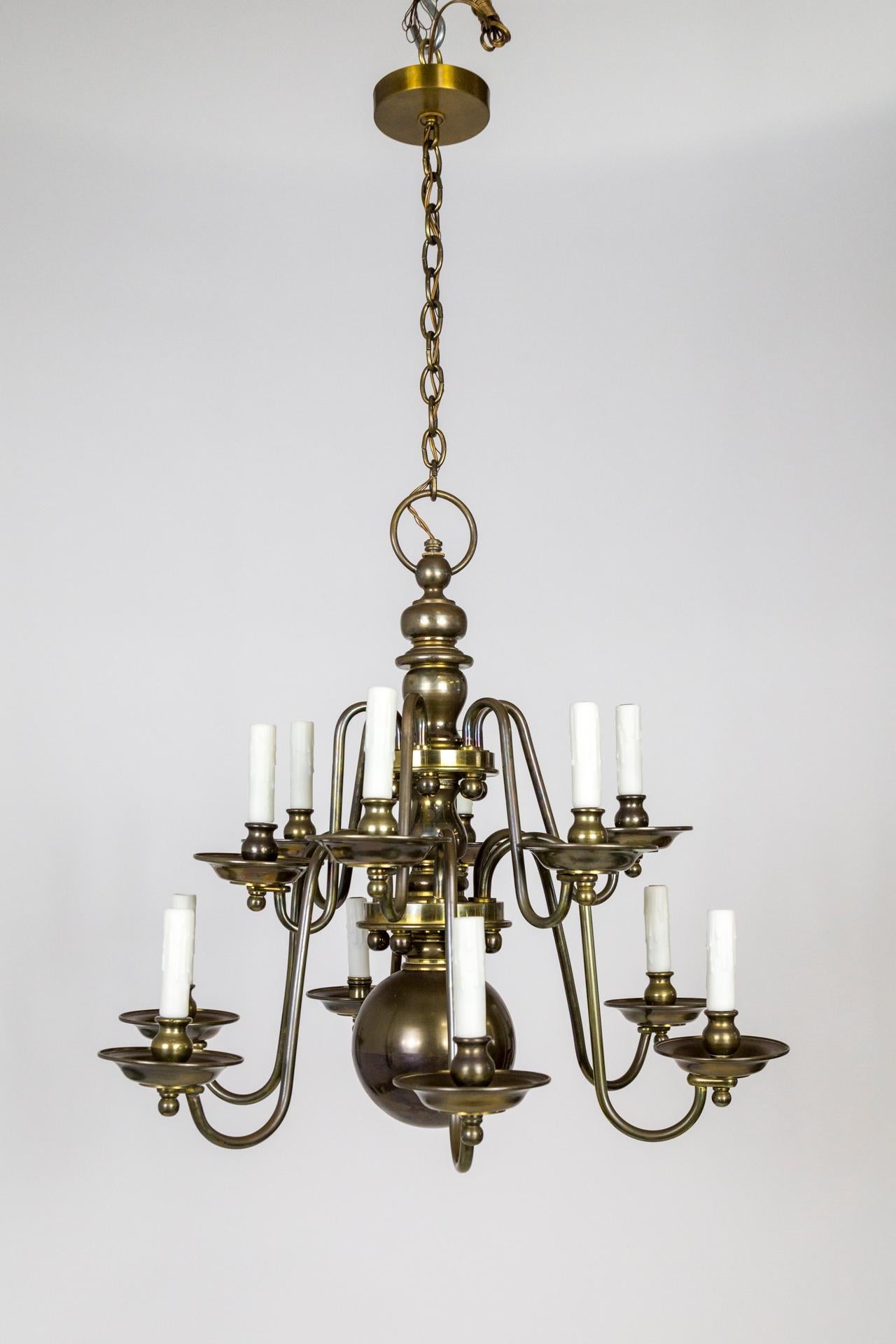 Un lampadario a 12 luci in ottone massiccio e pesante, in stile barocco olandese, meravigliosamente proporzionato con un'enorme sfera centrale e accenti di sfere più piccole sui bracci, sul supporto centrale e sui bobeches. Una bella patina con