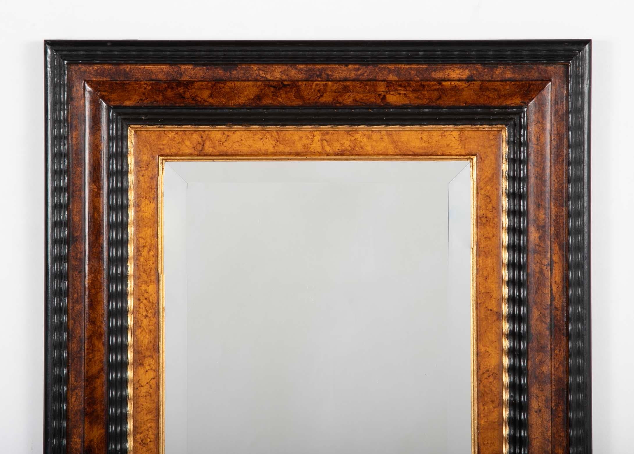Miroir de style baroque hollandais avec moulure ondulée ébonisée en relief encadrant des sections peintes en faux bois et une moulure intérieure en bois doré. Un miroir très beau et élégant, qui, bien que de petite taille, a une présence démesurée.
