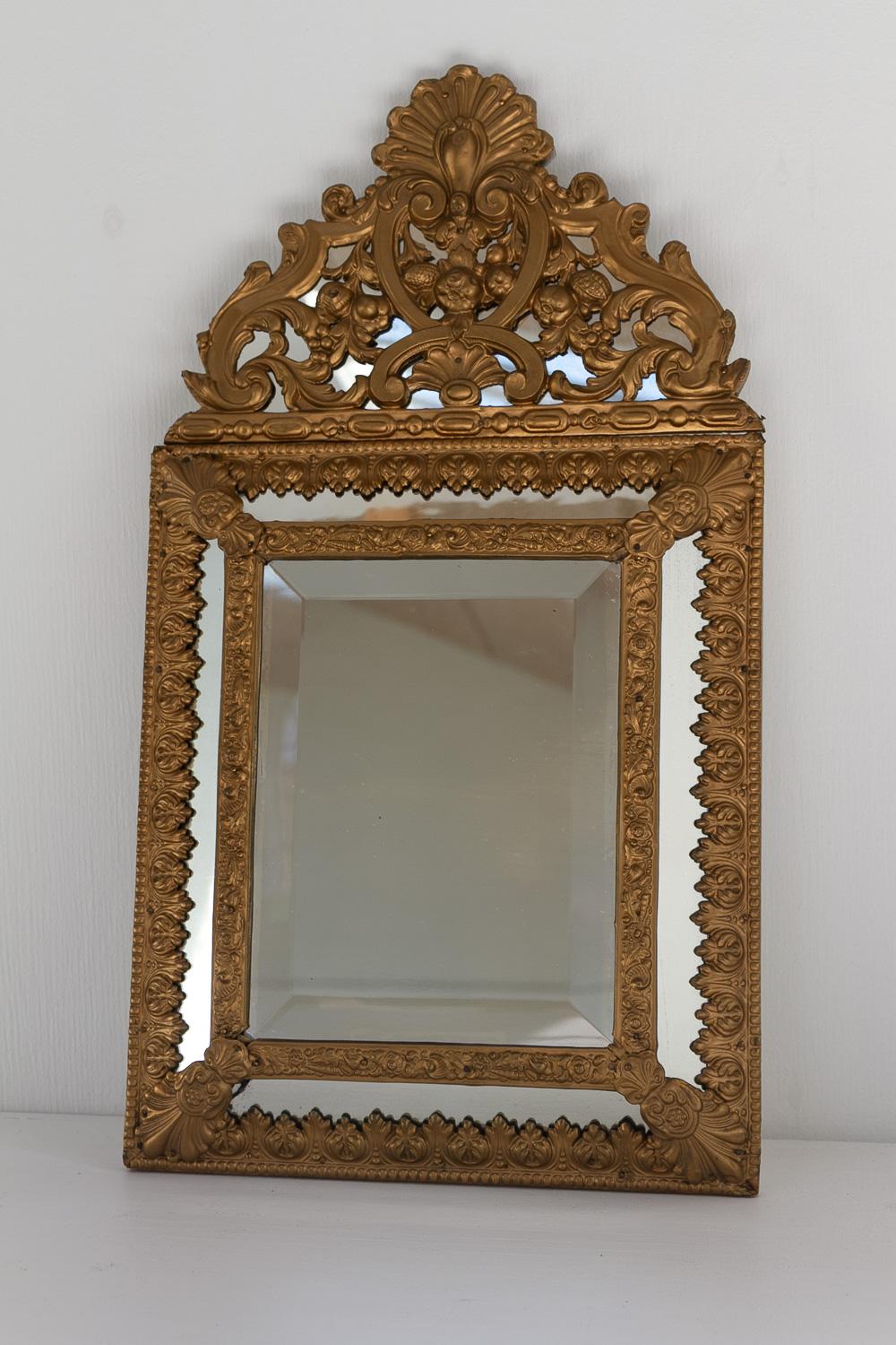 Specchio a cuscino in stile barocco olandese, dorato e repoussé, fine del XIX secolo.

Specchio olandese a cuscino con vetro a specchio centrale smussato. Cornice in legno e intricata lavorazione in ottone color oro. 
Questo specchio di piccole