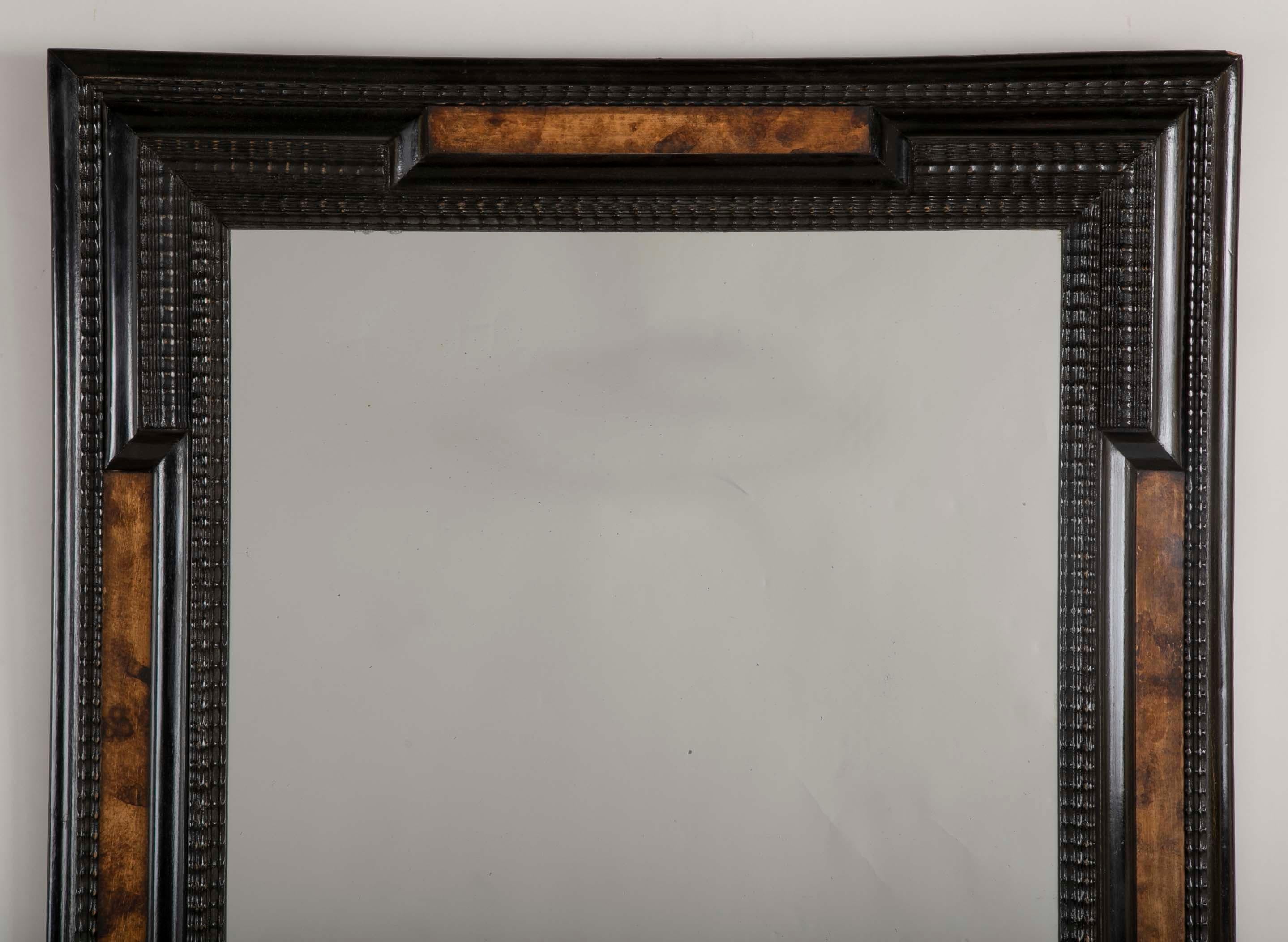 A beautiful Flemish Baroque style mirror having a faux tortoise panels and ebonized frame.