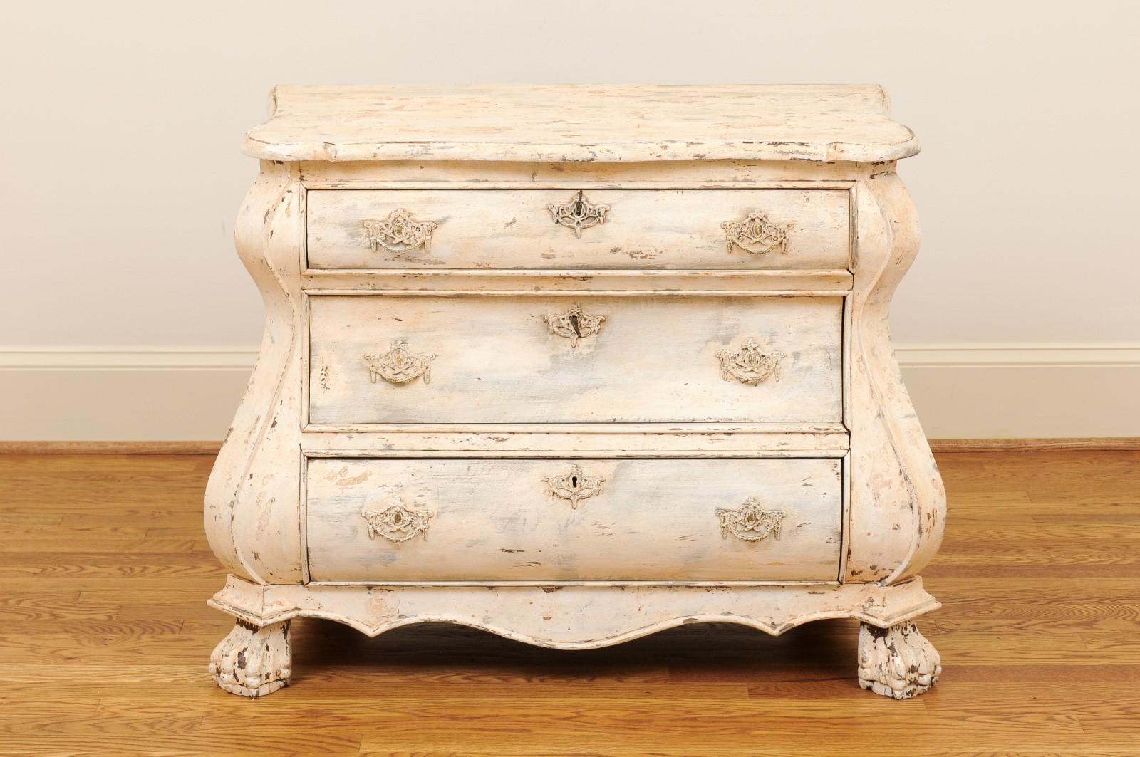 A Baroque style Dutch painted wood bombé three-drawer commode from the late 19th century. This painted commode was born in the Netherlands in the 1890s and features a shaped top with beveled edges over three drawers, the upper one being smaller than