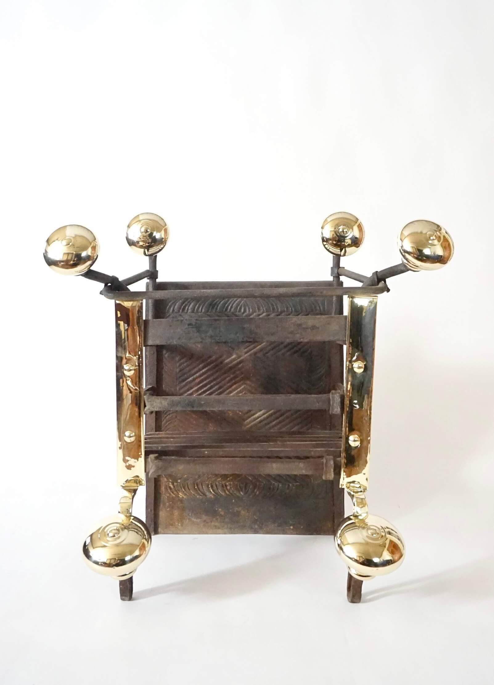 A wonderful 17th century and later Dutch Baroque period wrought iron and brass fire grate of large scale, the rectangular basket with cast-iron back having foliate and geometric designs connected by wrought supports, the front brass clad, with