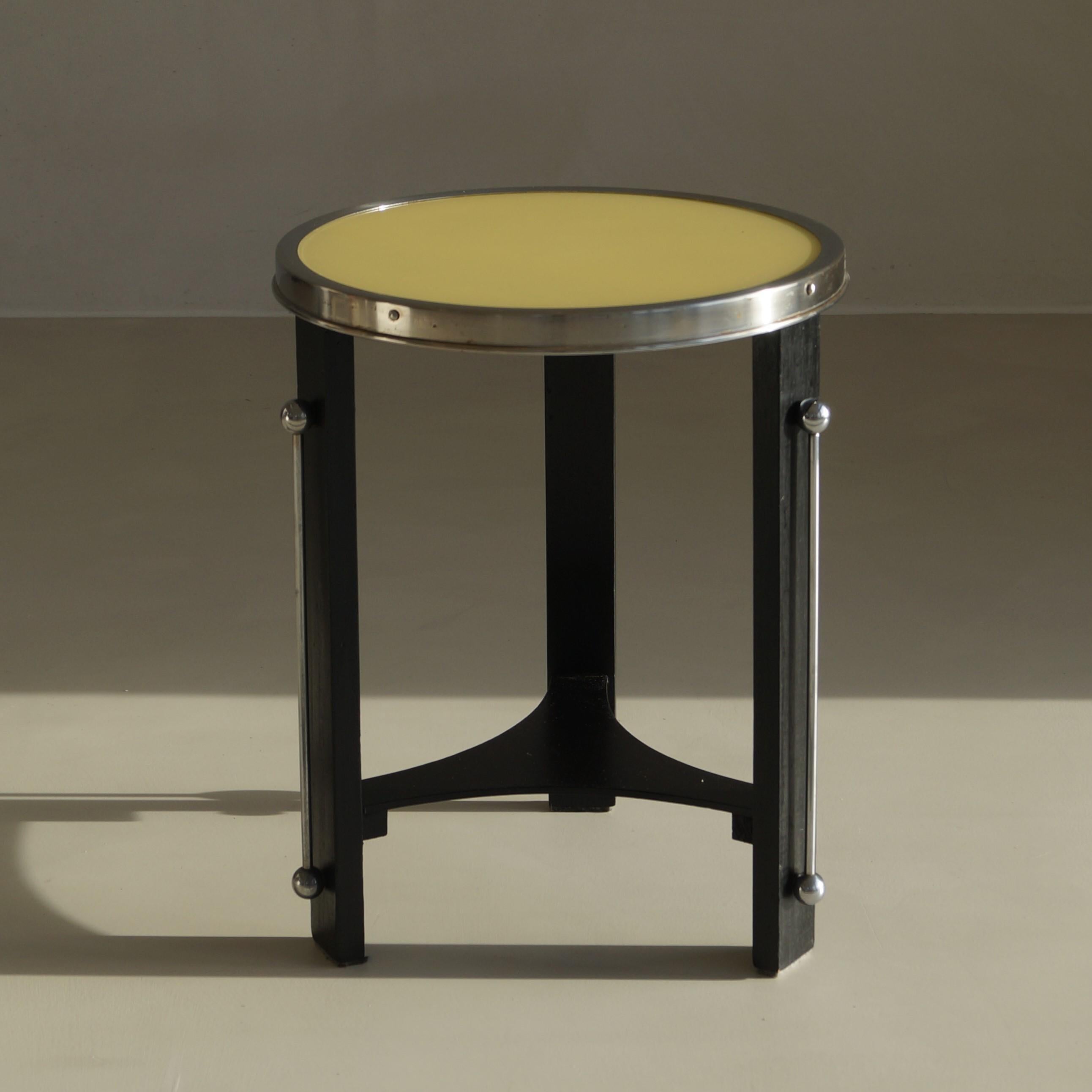 Very decorative 1930s Dutch bauhaus table with elegant metal decorations on the tablelegs, and a (glass) yellow top. The unusual colour in combination wwith the silver accents gives it a very fresh and clean appearance.. The modest size makes it an