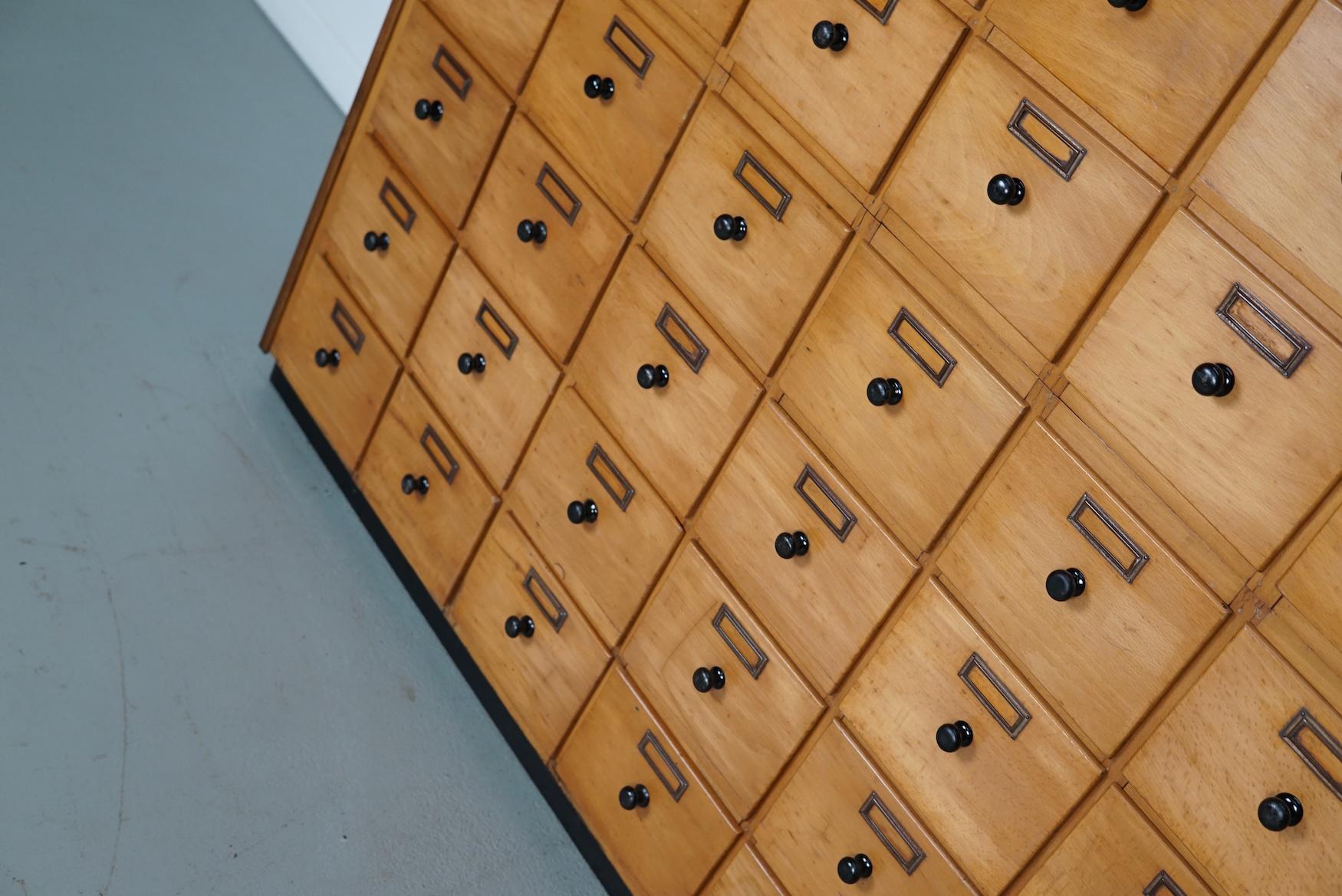 Questo mobile da officina è stato realizzato in faggio nei Paesi Bassi intorno agli anni '50 e veniva utilizzato in un'officina per le attrezzature dei dentisti. Dispone di numerosi cassetti con simpatici pomelli neri. Le dimensioni interne dei