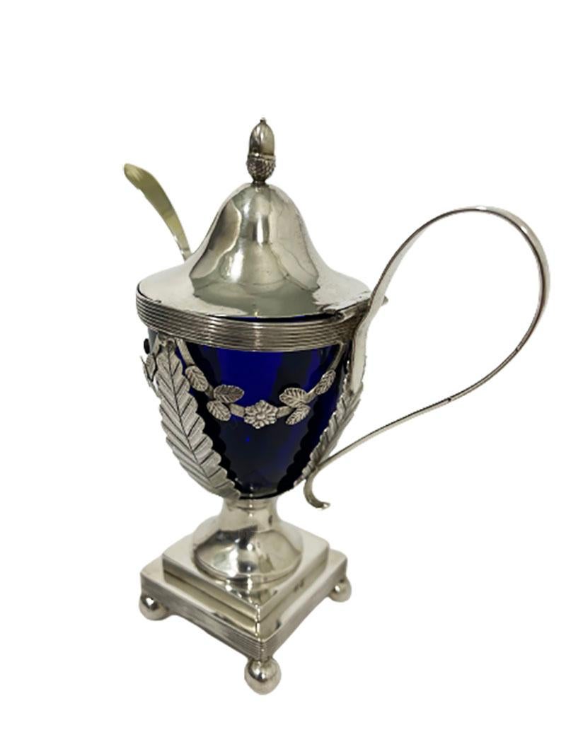 Dutch Blue crystal mustard pot with silver mount by Jan can der Cop, 1833

A silver mustard pot with a blue crystal pot and a silver gilt spoon. A silver mount of a flat plate engraved Empire style leaf motif on a square base raised on 4 balls.