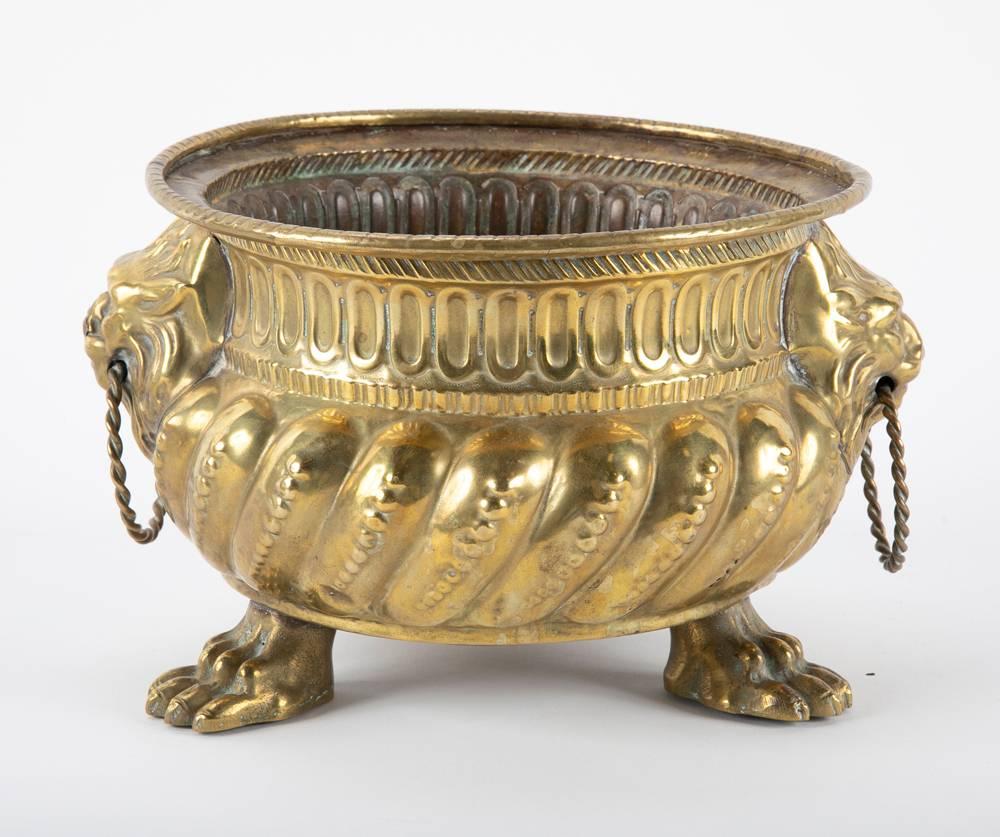 A pair of cachepots or jardinieres made of hand-hammered brass in the Dutch Baroque style. With lobed bottoms supported by tripod paw feet, each with lion heads with rings in their mouths that serve as handles. Very handsome as planters, or