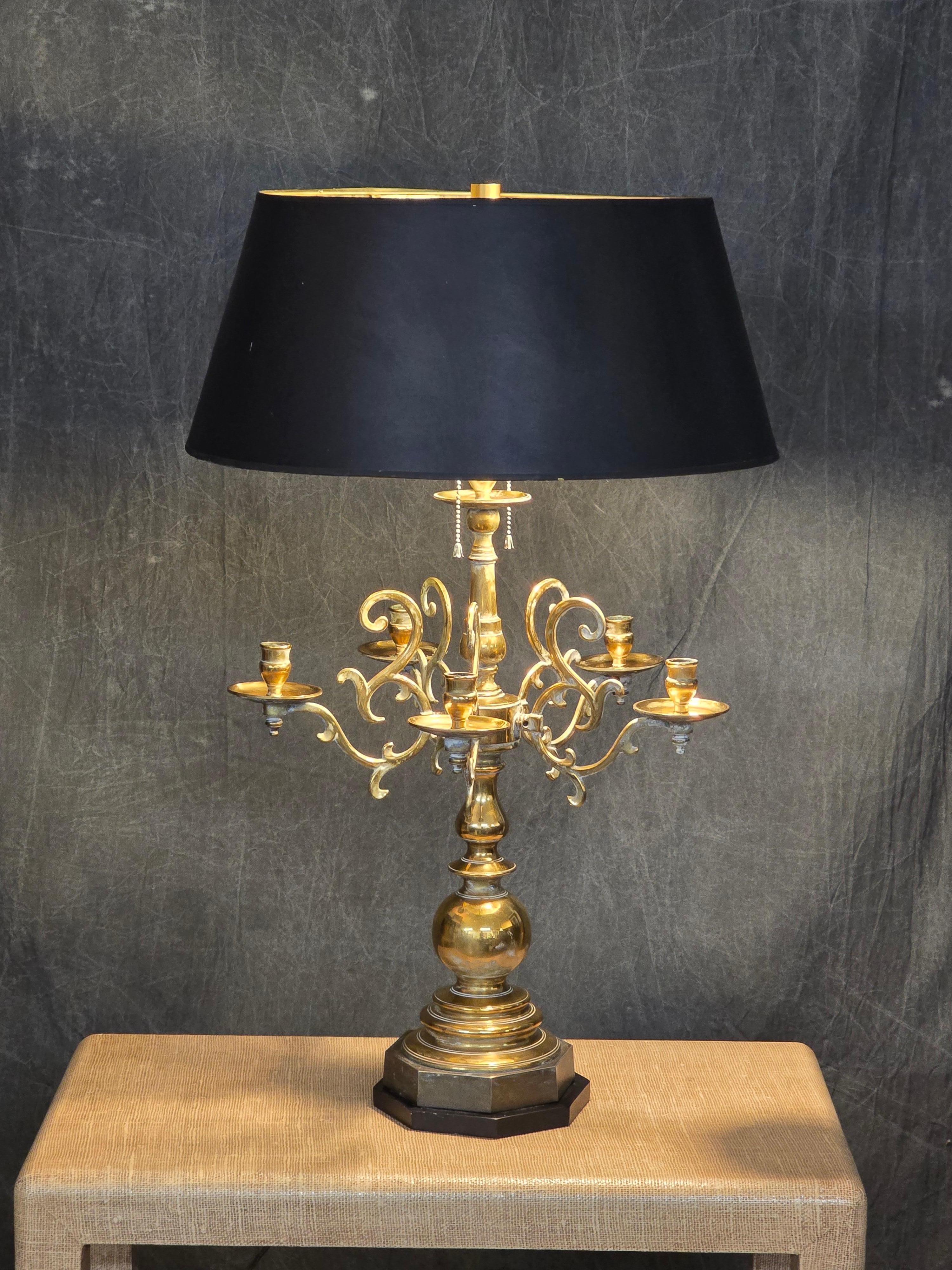 Raro candelabro holandés de latón, mediados del siglo XVIII, adaptado posteriormente como lámpara de mesa por Chapman, hacia la década de 1970. El candelabro conserva su base octogonal original, el vástago en forma de balaustre y cuatro brazos de