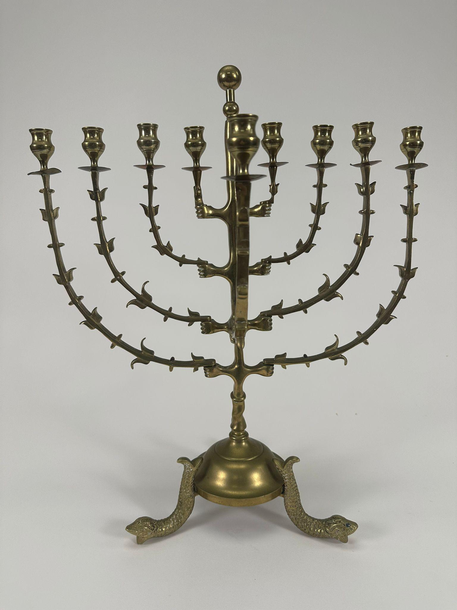 This striking brass menorah, crafted in the Netherlands during the late 19th century, exemplifies a blend of artistic craftsmanship and symbolic meaning. Measuring approximately 20 inches in height and 17 inches in width, the menorah features an