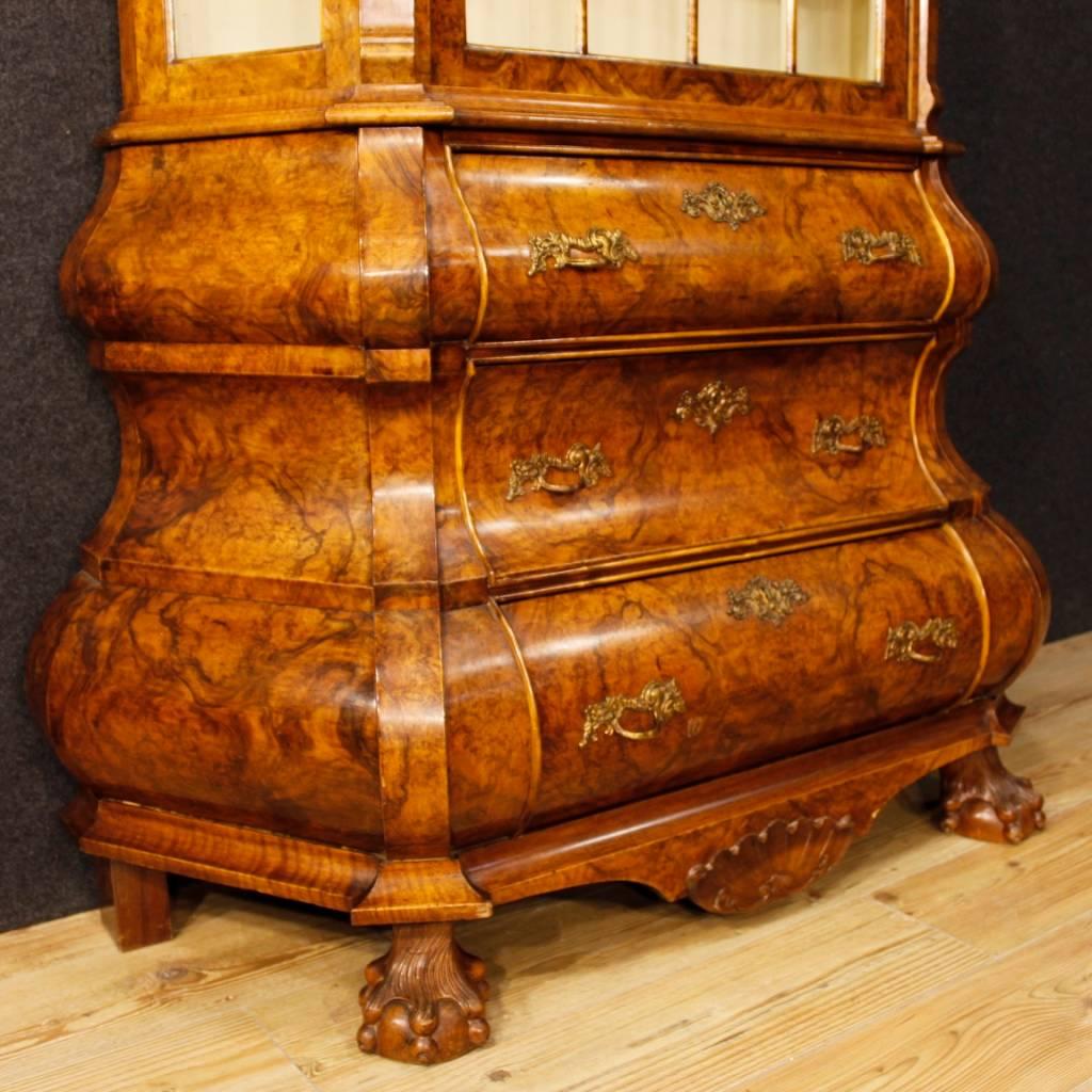 Dutch showcase from the mid-20th century. Double body cabinet veneered in burl walnut wood with zoomorphic front feet and moulding carved in mahogany. Display cabinet with three drawers in the lower body and one door in the upper body. Furniture