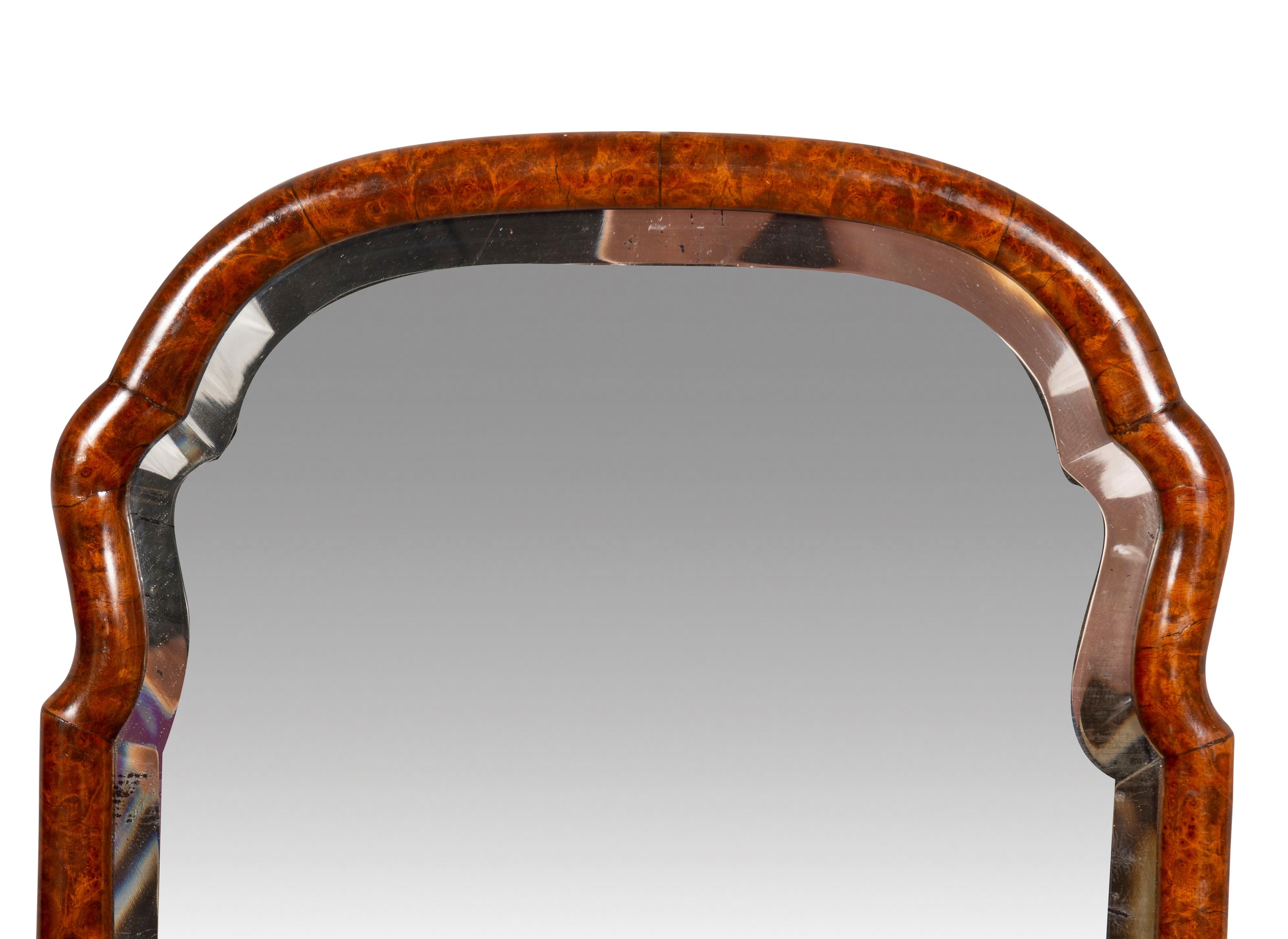 Arched beveled mirror plate set in a conforming burl walnut frame.