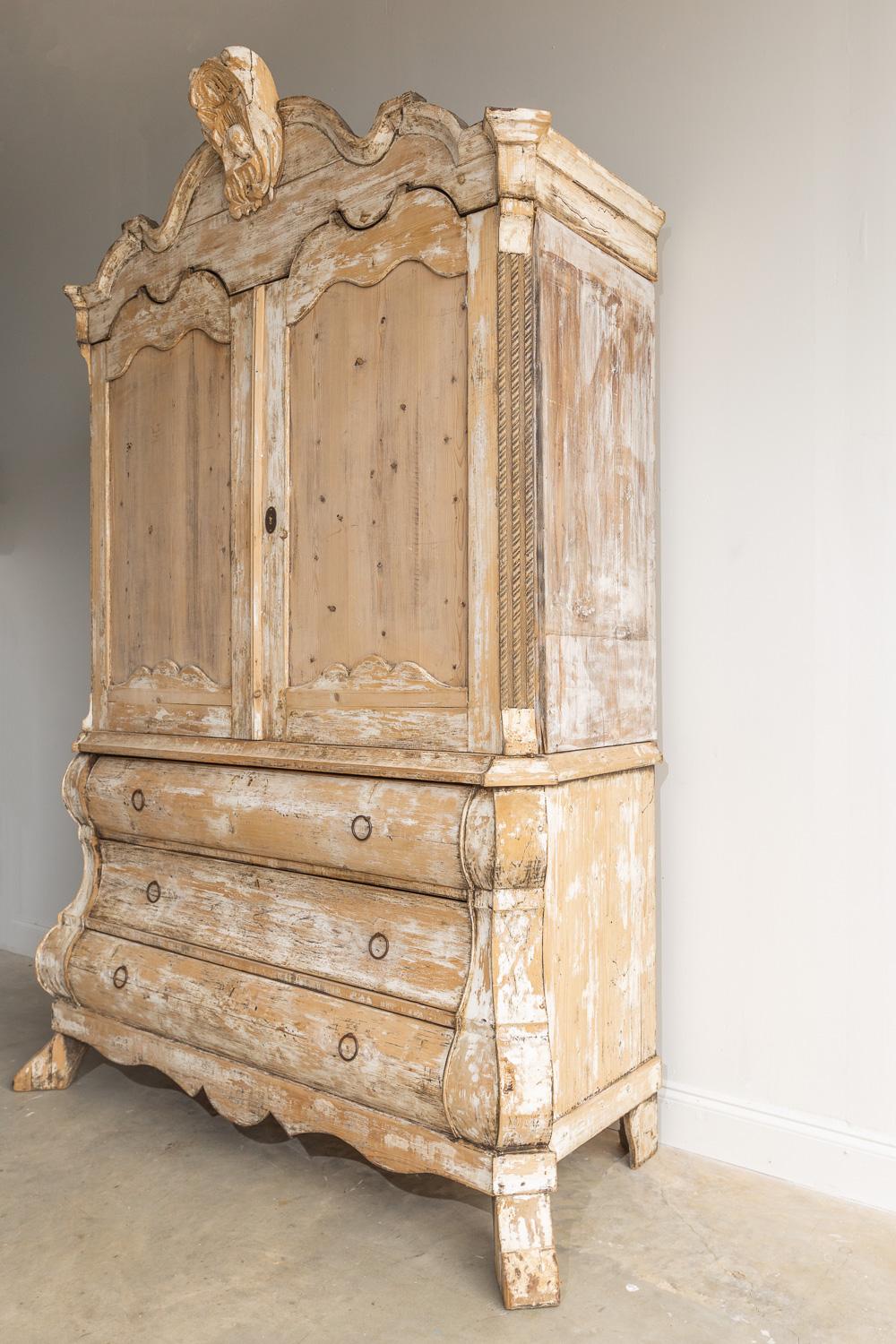 This beautiful 18th Century Dutch Bombay credenza has curves and details that are unlike any other piece. This enfilade is made of dry scraped pine and has a beautiful carved crest at the very top. There are also lovely carved roping details on the