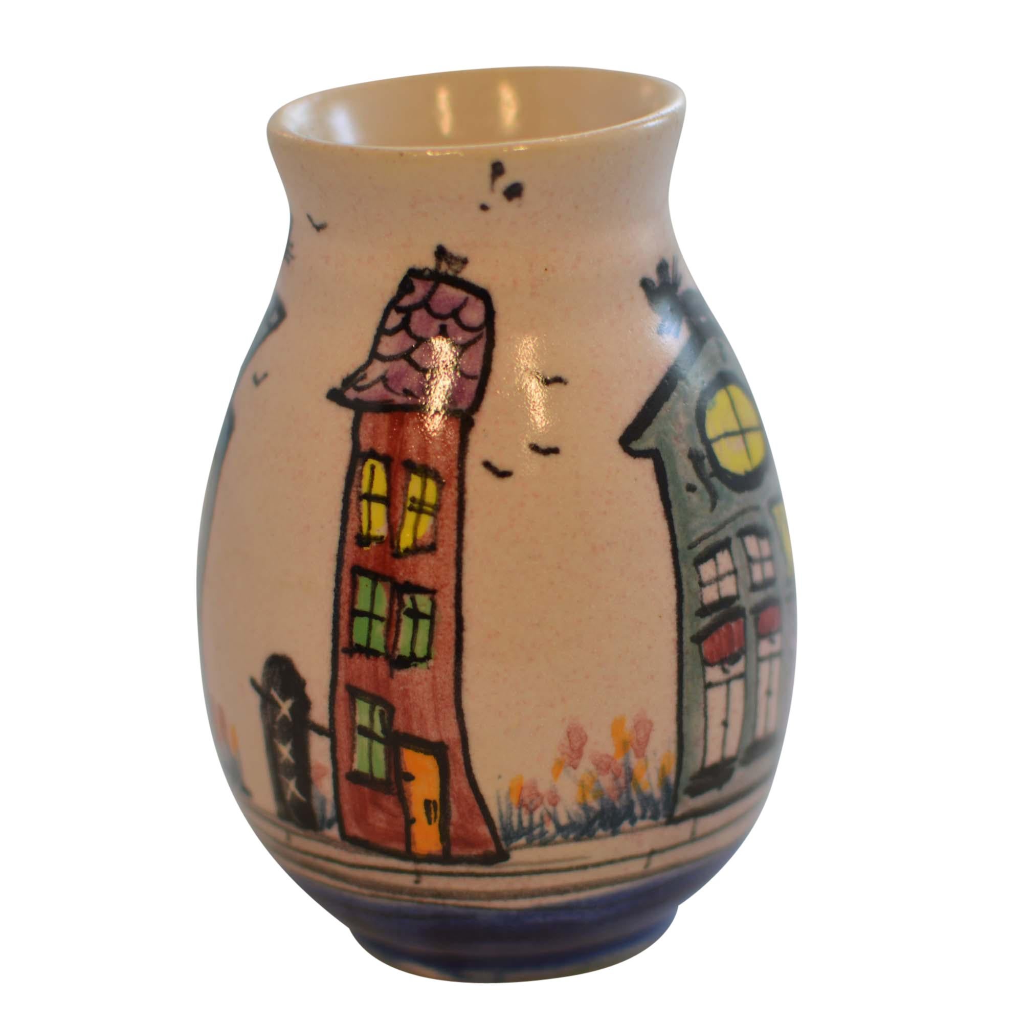 handcrafted bud vase is the work of Anna Maria Preuss. The vase features a scene of hand painted canal front homes with whimsical cats sitting atop homes, one sits on a green house while another is on the blue house. Anna's mark is on the bottom.