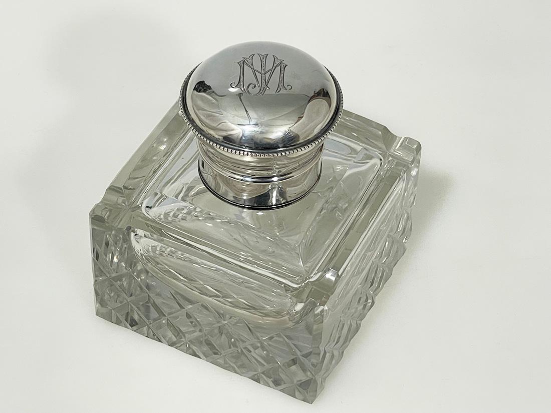 Dutch clear crystal with Silver Inkwell, Mid 20th Century

An inkwell, made of clear crystal glass with a silver cap, made in The Netherlands. The crystal glass at the bottom has a crystal cut star. each side have a ridge at the front to place the
