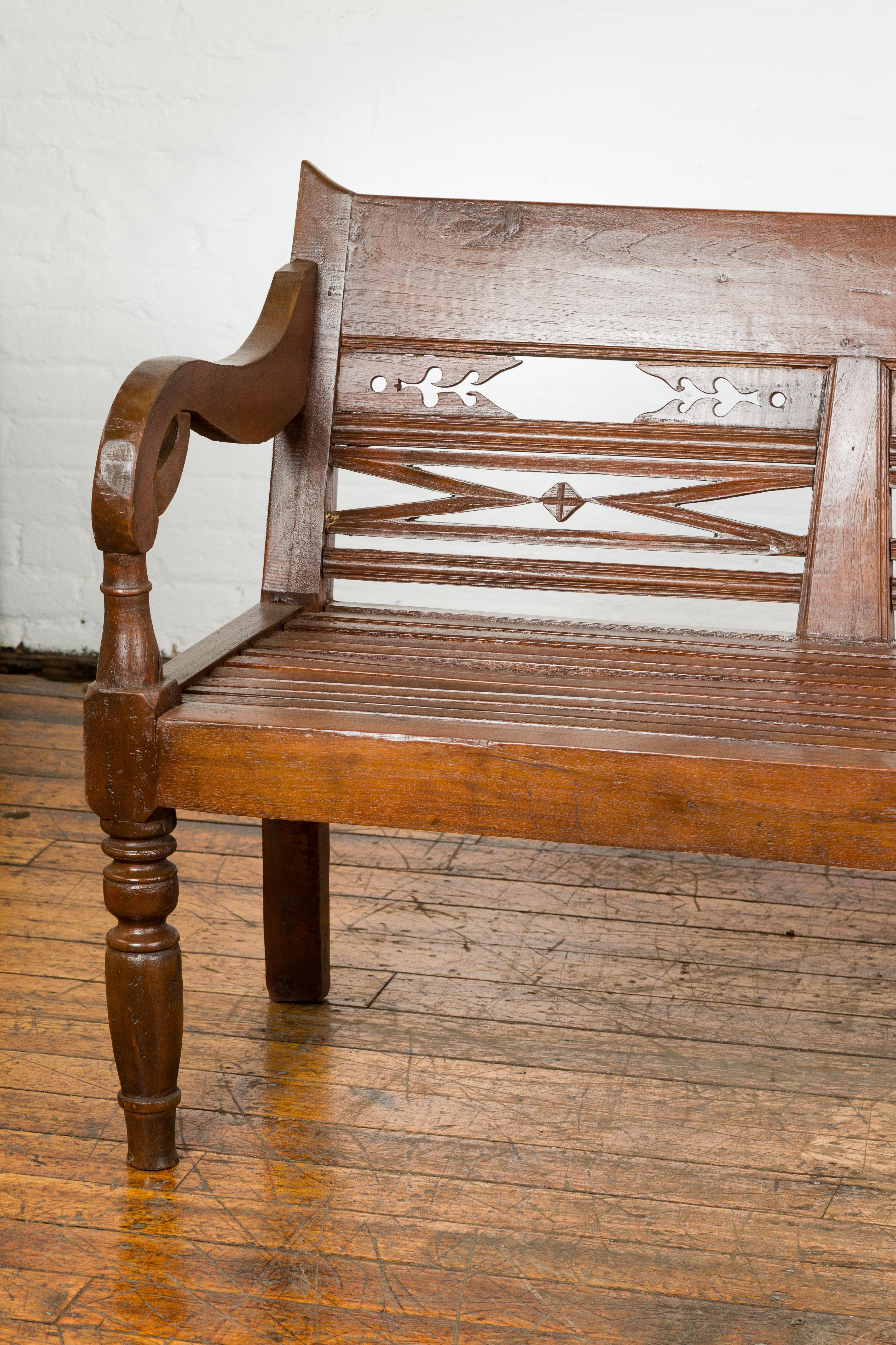 Indonesian Dutch Colonial Bench with Carved Back, Scrolling Arms and Turned Baluster Legs For Sale
