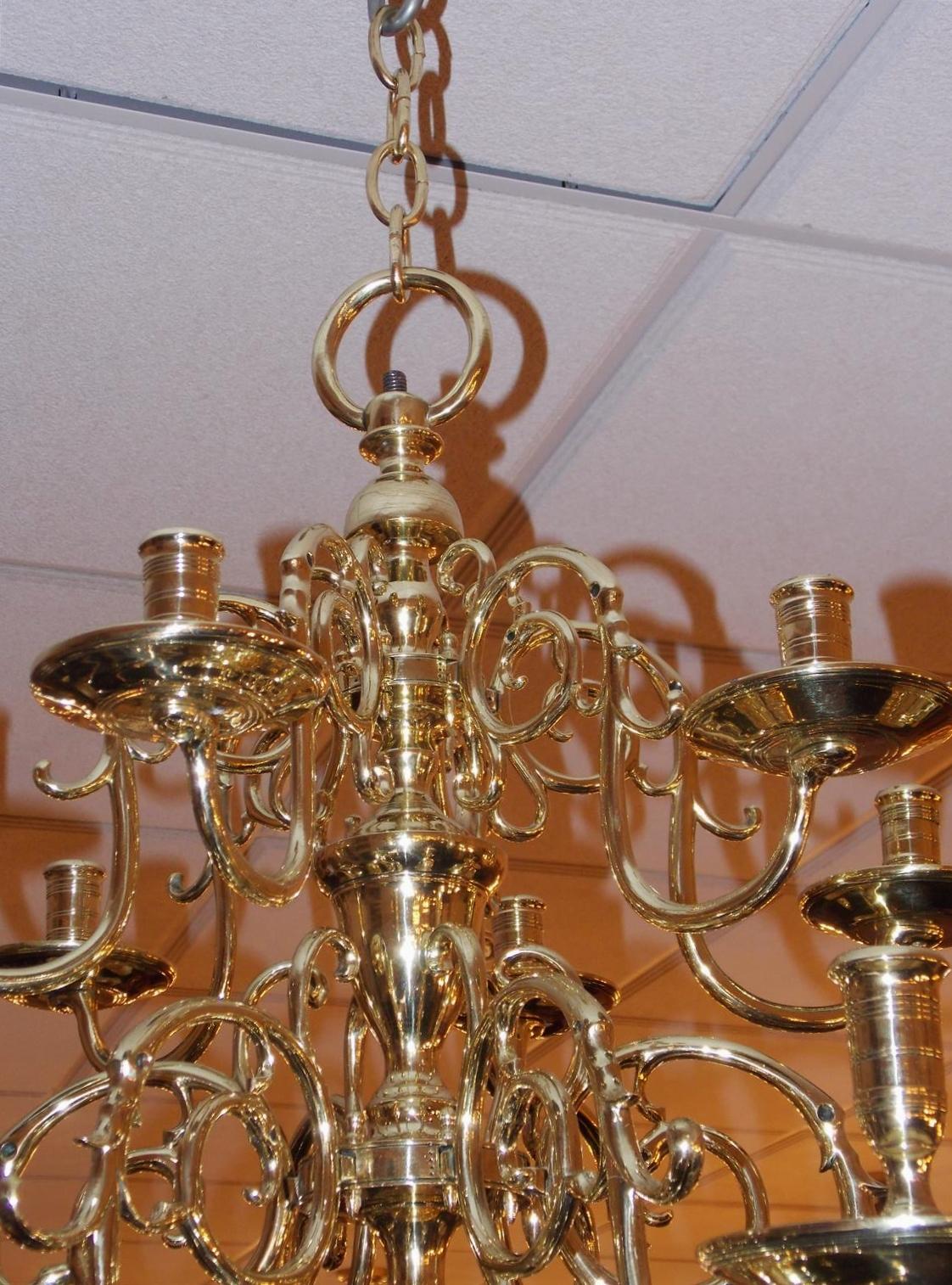 Dutch Colonial three-tier brass eighteen light chandelier with scrolled decorative arms, original bobeches, centered bulbous column, and terminating on a lower large ringed ball with ring finial. Candle powered and can be electrified if desired,