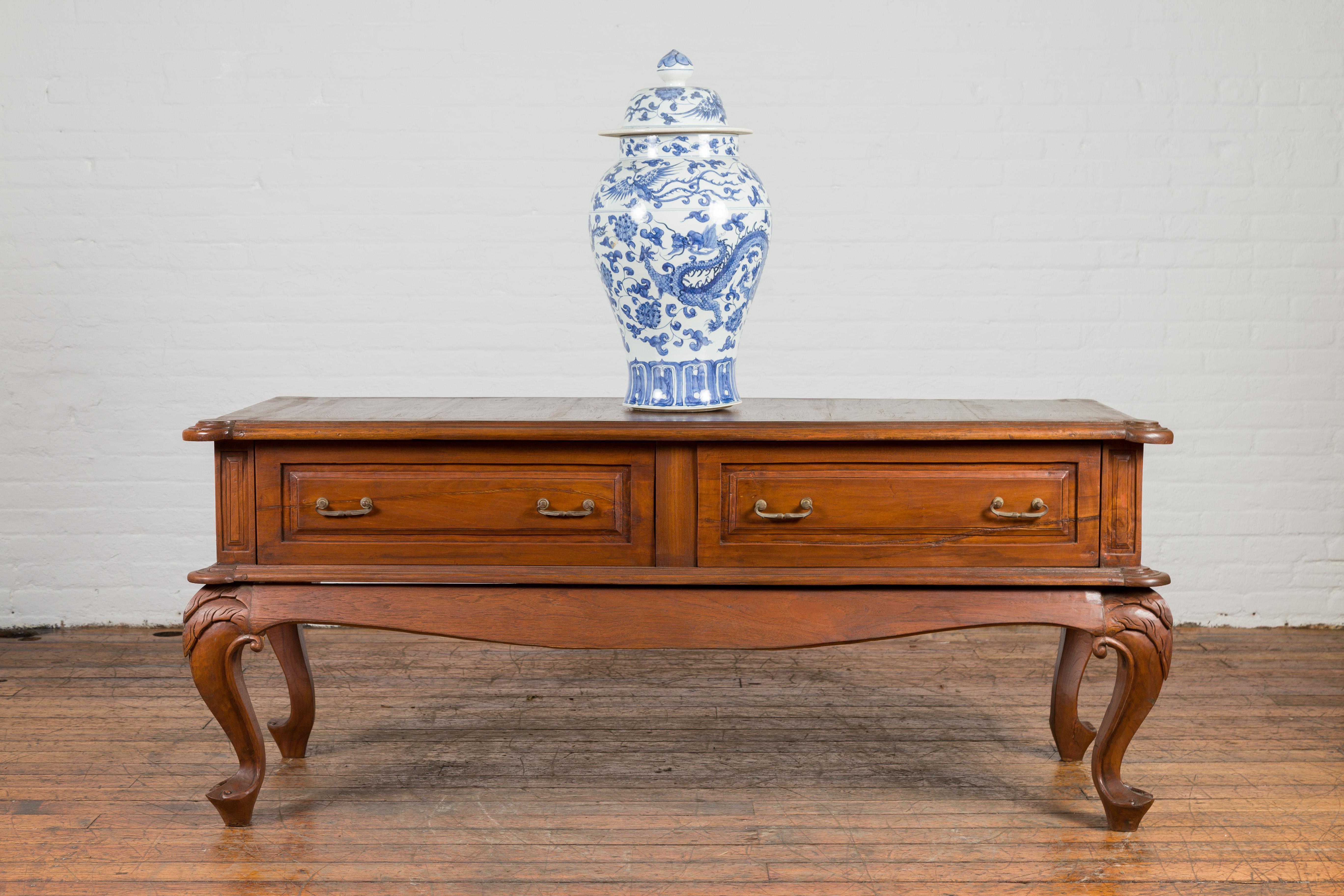 An antique Indonesian Dutch Colonial period low table from the early 20th century, with two drawers and cabriole legs. Created in Indonesia during the early years of the 20th century, this Dutch Colonial low table features a rectangular top with