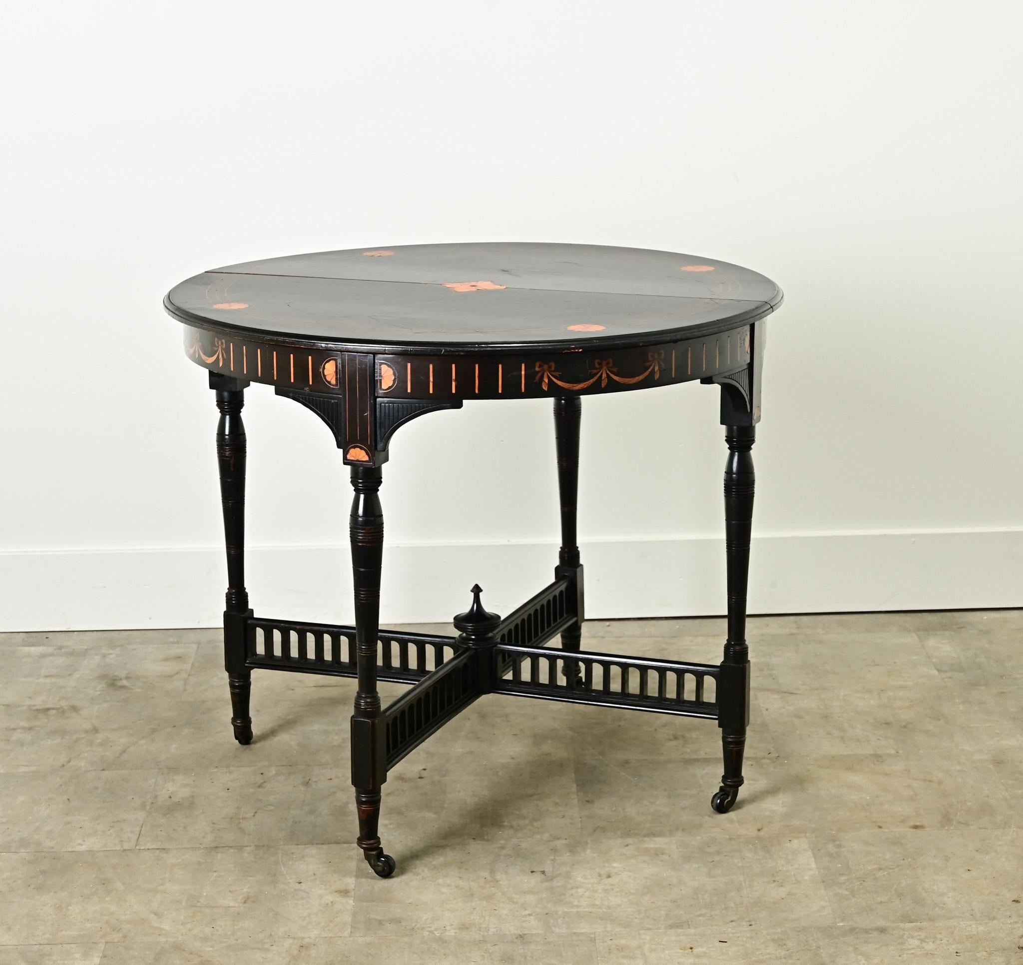 A colonial ebonized mahogany gueridon made in the Netherlands. This interesting round table has an ebonized mahogany finish with mahogany inlay designs on the top and surrounding the apron. Four turned legs are connected by a pierced X-shaped