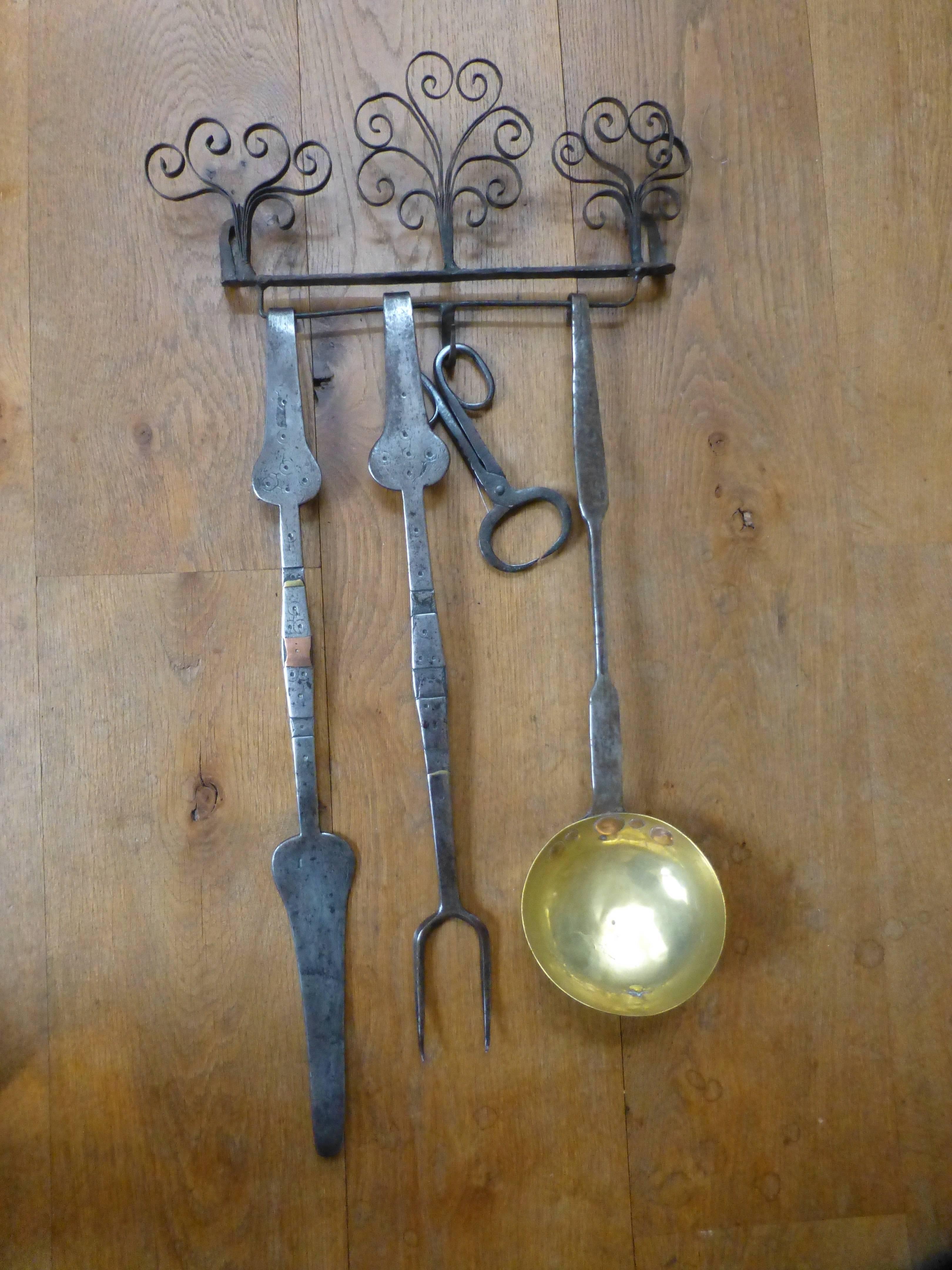Rare set of 17th century fireplace tools used for cooking in an open fire. The tongs were used to pick up rock candy (sugar). The set and hanger are made of wrought iron and brass with copper and brass inlaid details. The tools have various