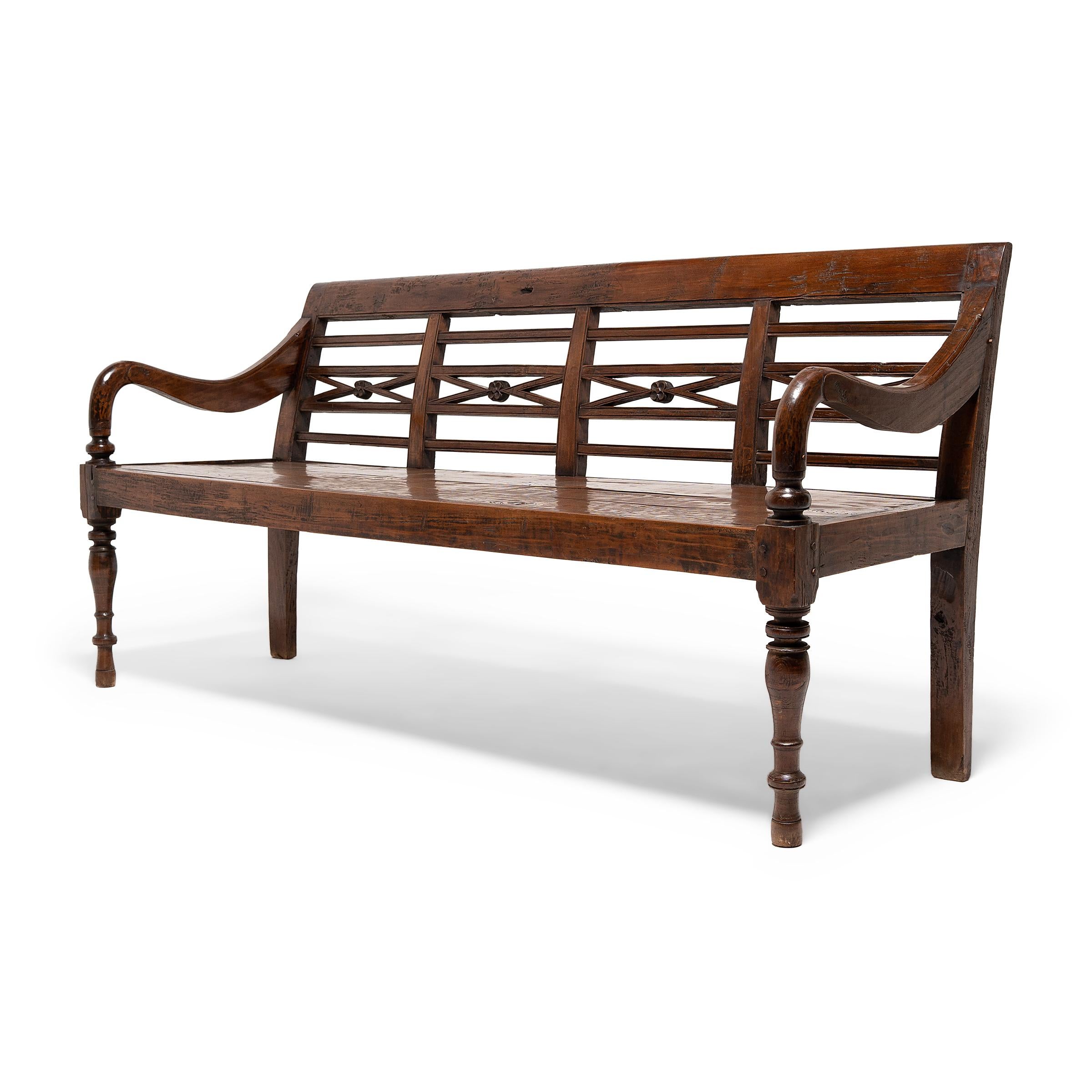 This charming Dutch Colonial garden bench comfortably seats three and makes the perfect addition to a sunroom, patio, or entryway. Crafted in Indonesia in the late-19th century. The bench features a solid wood seat, turned post front legs, and
