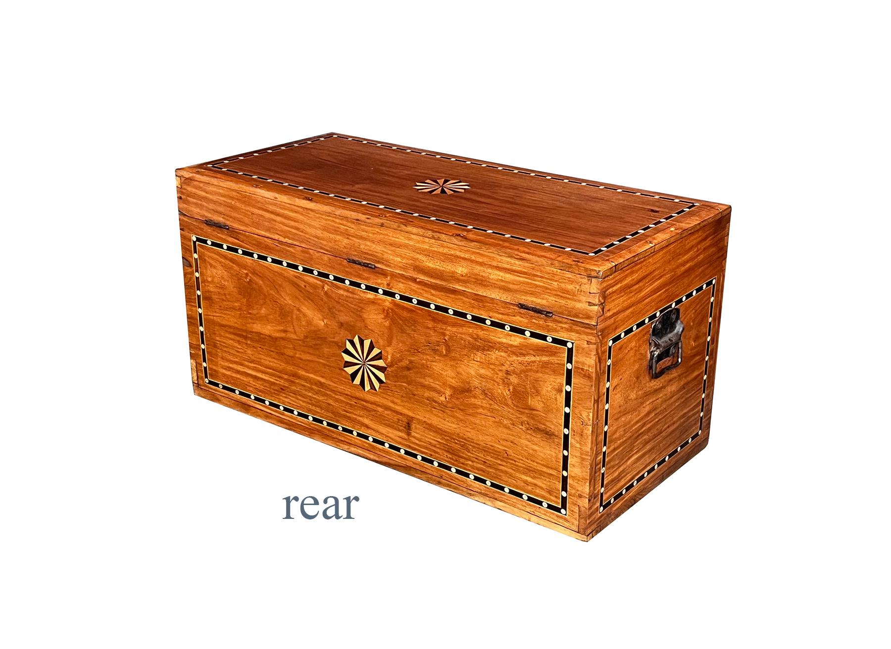 le couvercle rectangulaire à charnière repose sur un corps conforme flanqué de poignées en fer forgé ; orné sur tous les côtés d'une bande périmétrique en bois exotique incrusté d'os ; l'avant, le dessus et l'arrière sont centrés sur un motif en