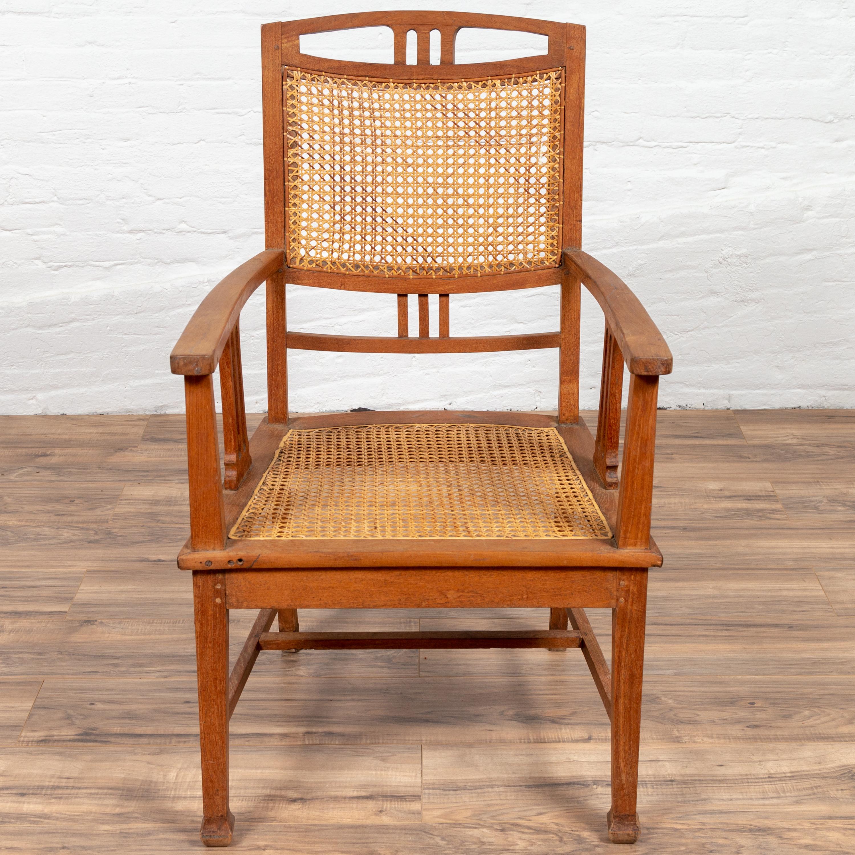 Ancien fauteuil colonial hollandais en teck du début du 20e siècle, avec assise en rotin et motifs inspirés des triglyphes. Né dans les premières années du XXe siècle, cet élégant fauteuil en teck met en valeur l'esthétique raffinée du design