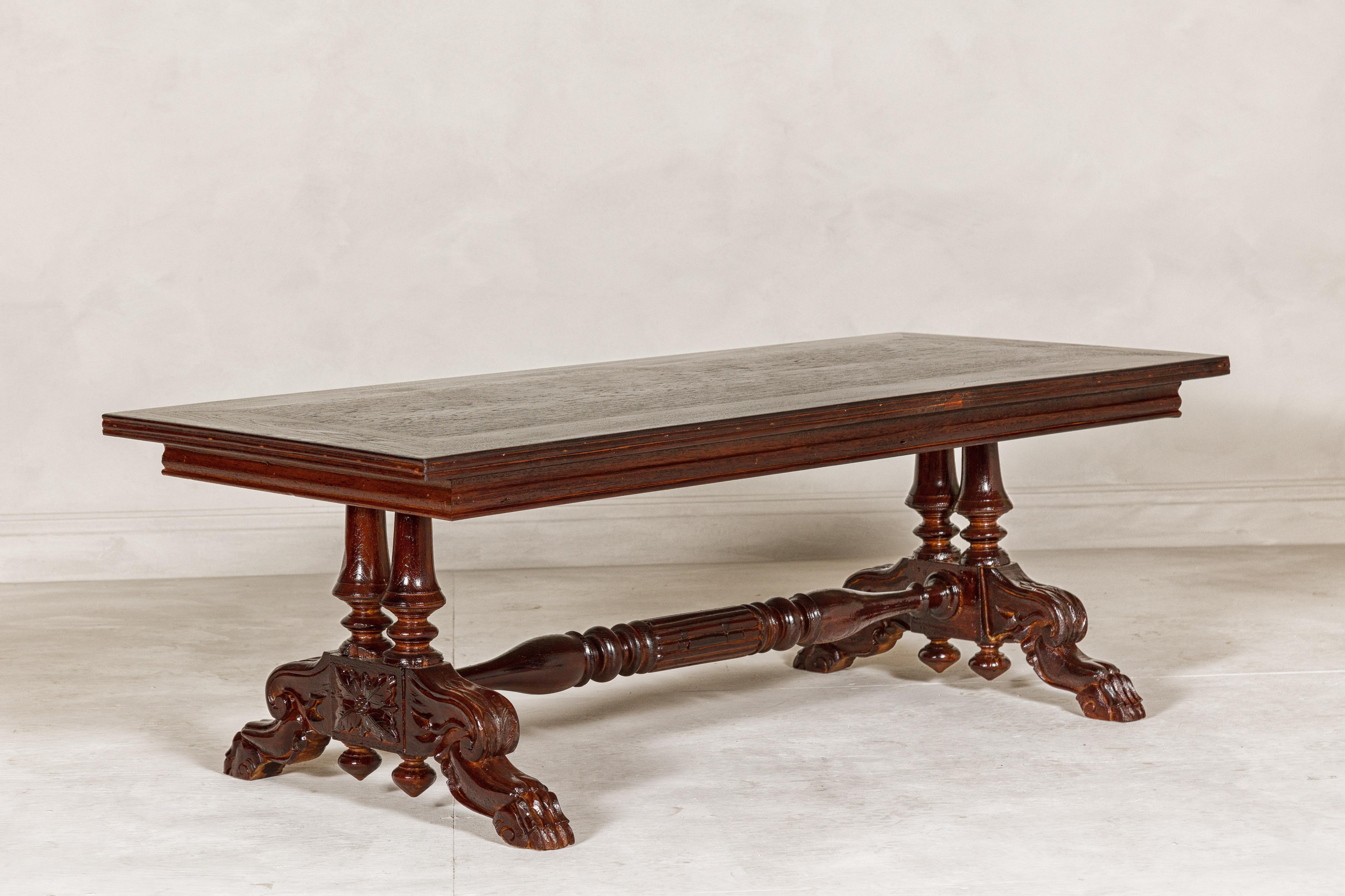 A long Dutch Colonial coffee table with carved lion paw legs. This long Dutch Colonial coffee table exudes a stately presence with its ornate and meticulously carved lion paw legs. The vintage piece, dating back to a time of exquisite craftsmanship,