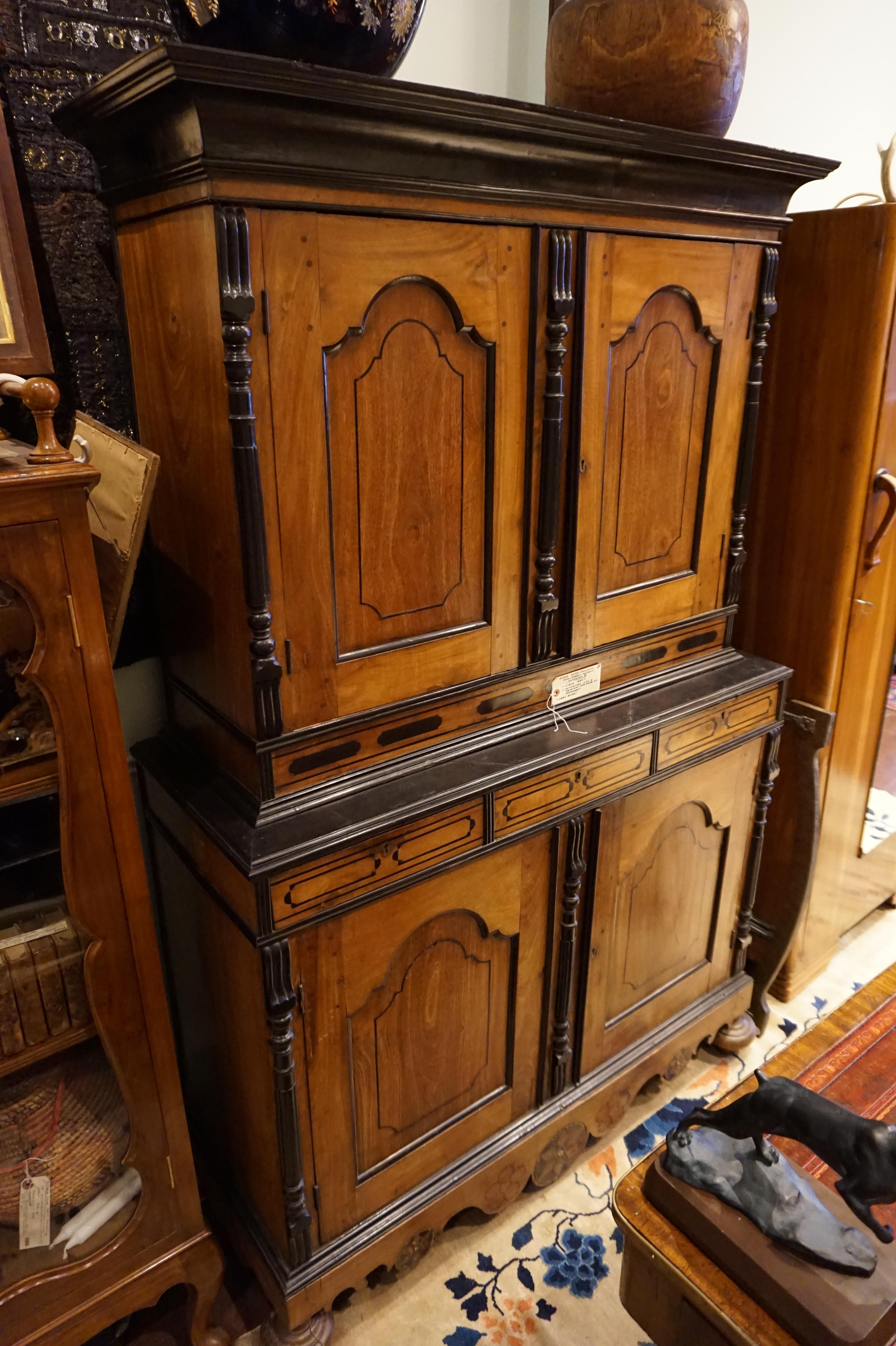 Exquisite Dutch Colonial cupboard hand-made from solid Teak and laced with Ebony. This piece dismantles into three pieces for ease of movement and exudes the elegance of bygone craftsmanship with fluted pilasters and crown mouldings in ebony