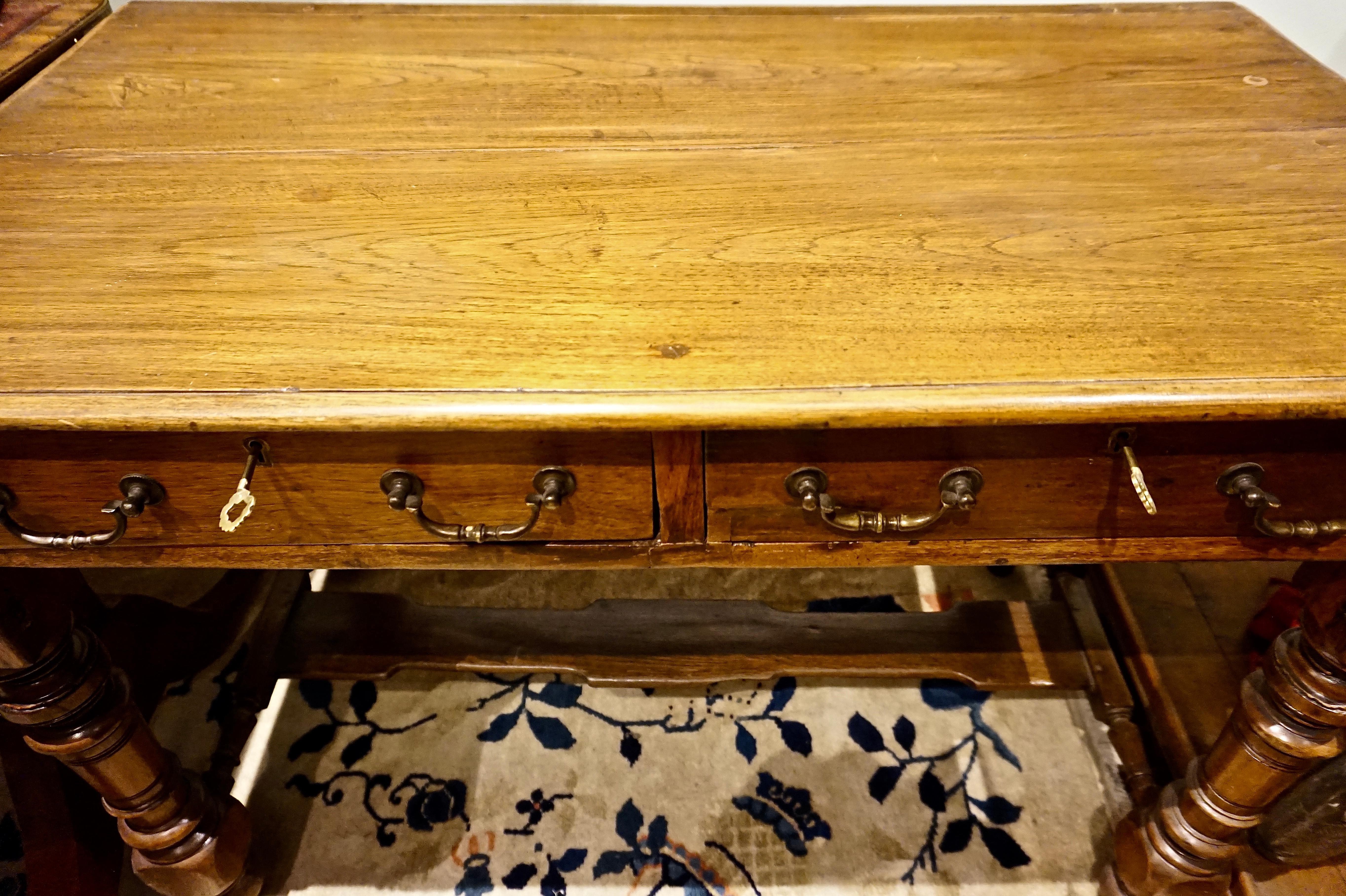 Dutch colonial teak desk with brass hardware.
Solid carved legs united by footrest stretcher. Old brass handles and peg work joinery throughout. Locks have been replaced at some point but come with keys and work. Some repair to tabletop,
circa