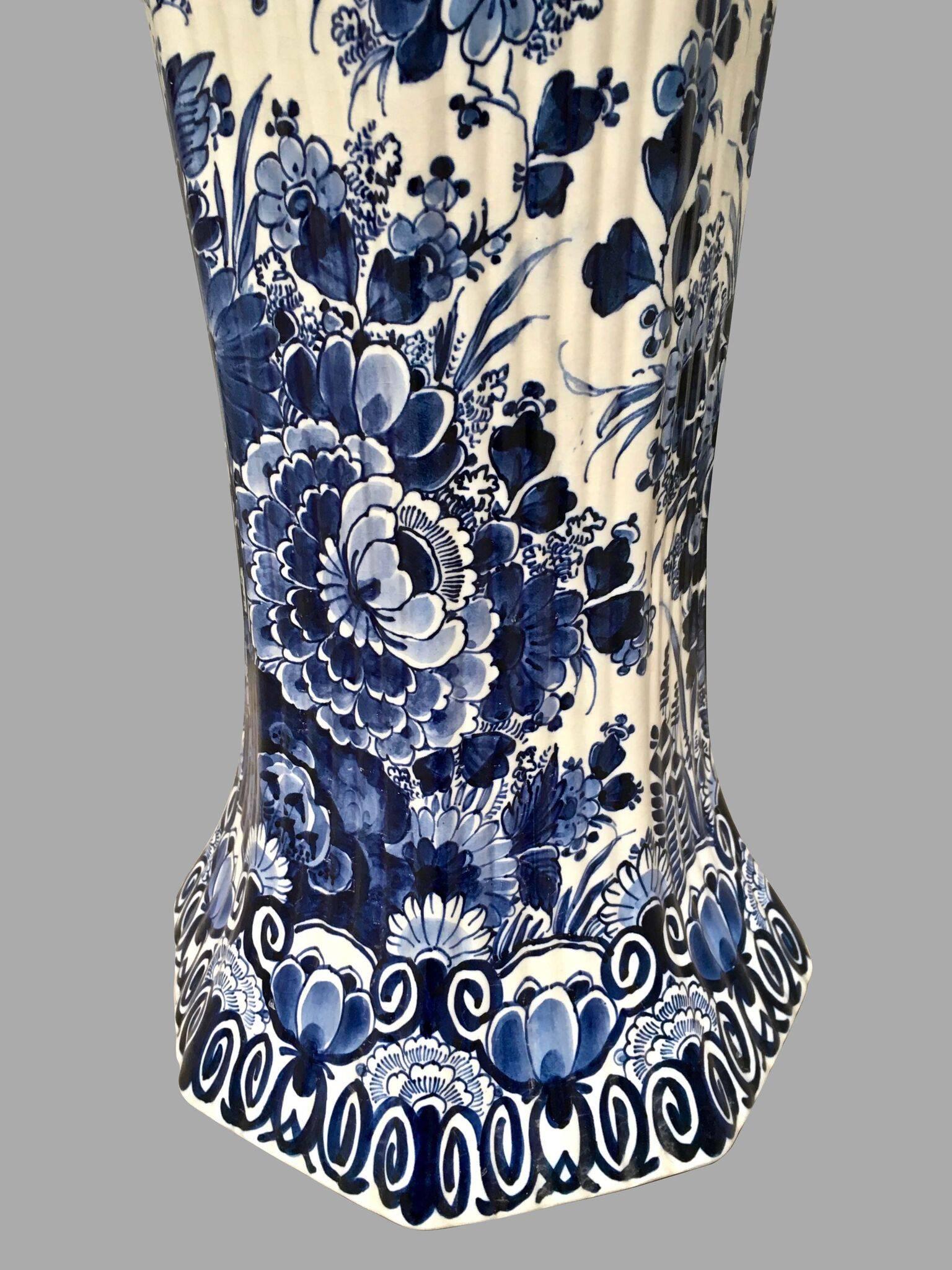 An attractive Dutch Delft tall blue and white vase with overall foliate decoration, the base of hexagonal form, the ridged body ending in a flared top. Signed, 20th century.