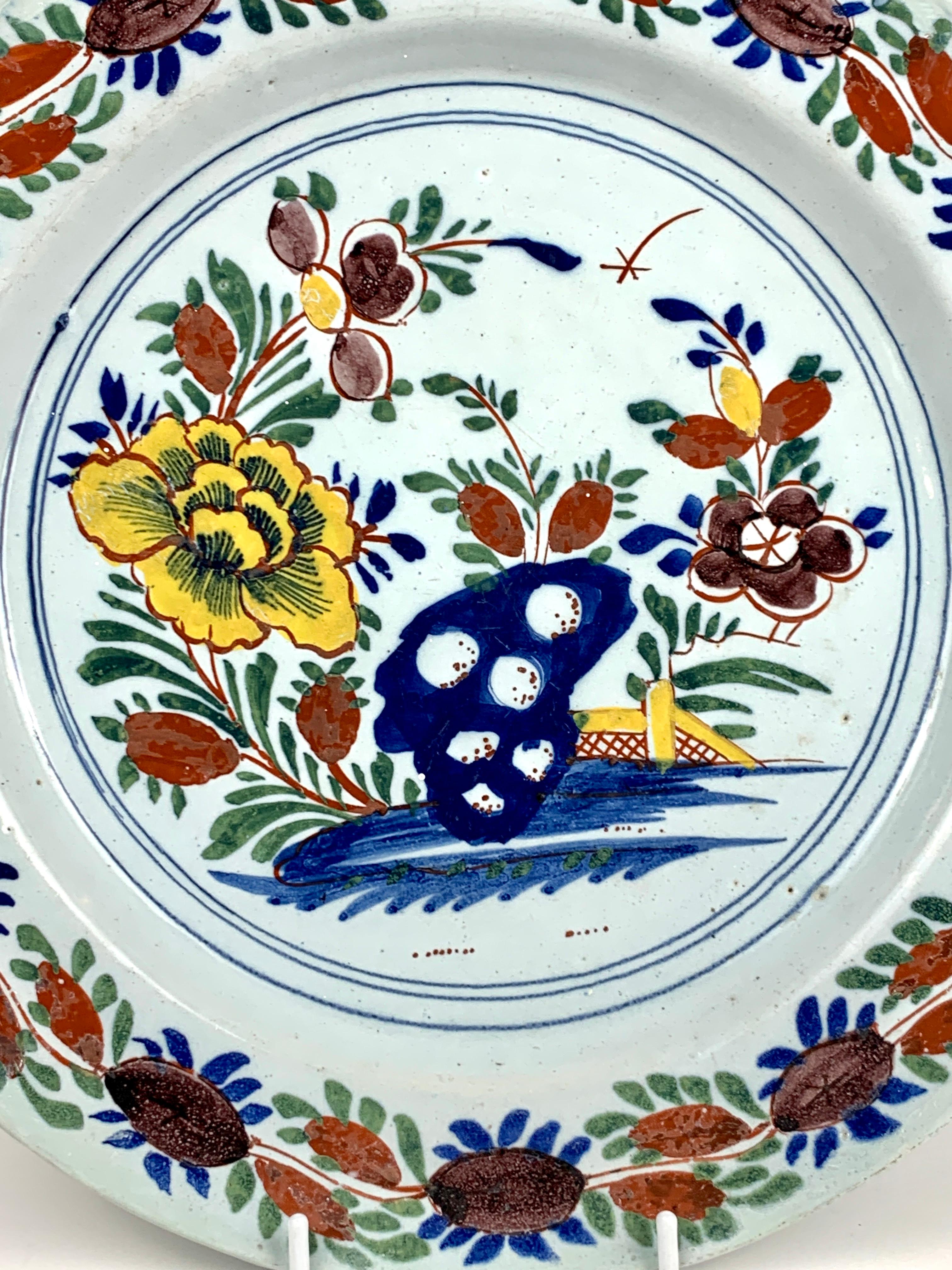 This antique Dutch Delft charger was made in the 18th century, circa 1770. 
It features a beautiful flower-filled garden hand painted in beautiful polychrome colors. 
We see a single large, bright yellow peony, other flowers painted in shades of