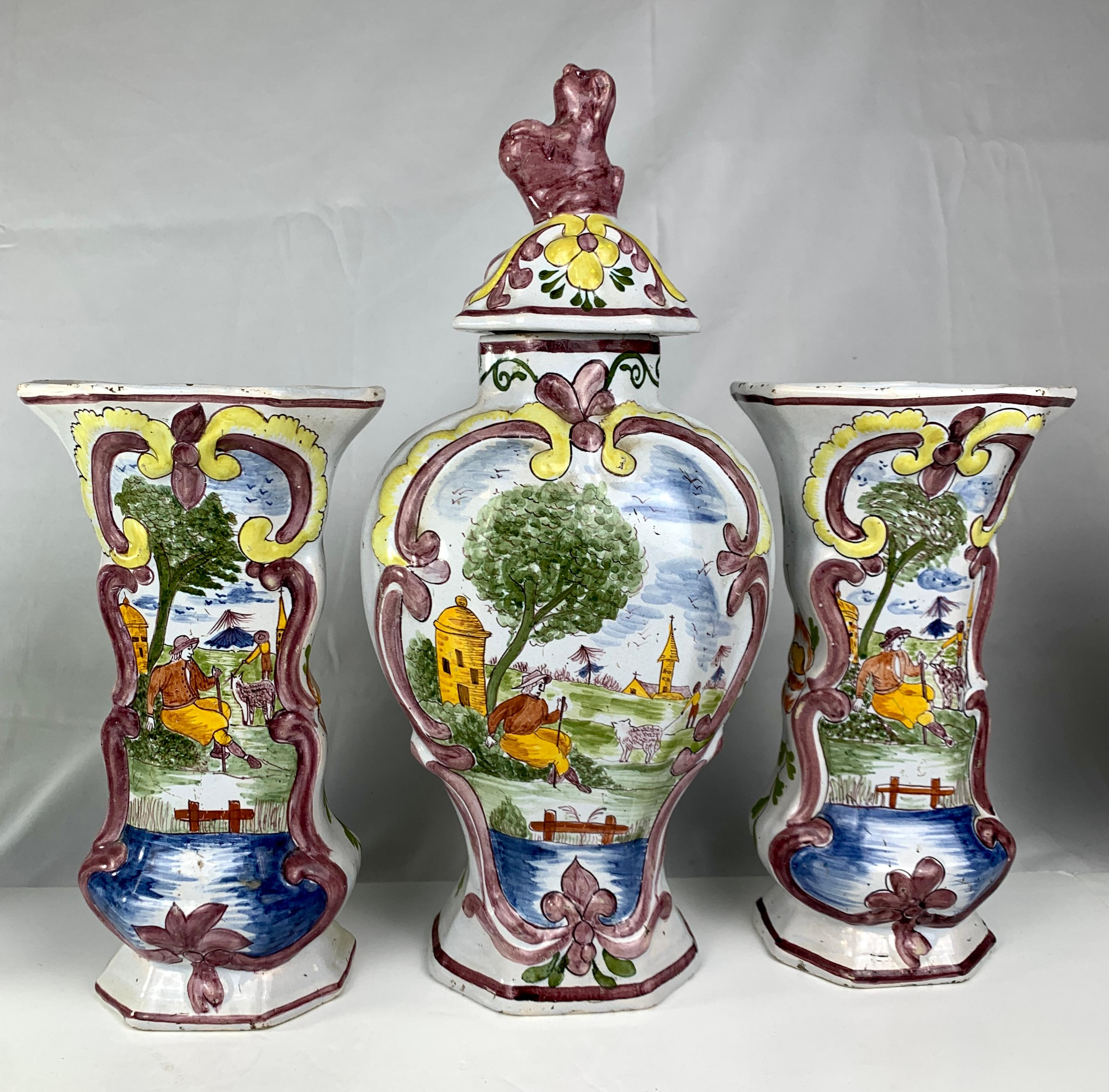 This charming Dutch Delft garniture comprises the traditional five pieces: two beaker vases and three baluster-form jars with their covers.
It is in excellent condition.
We see a romantic countryside scene with a shepherdess and sheep.
Sitting