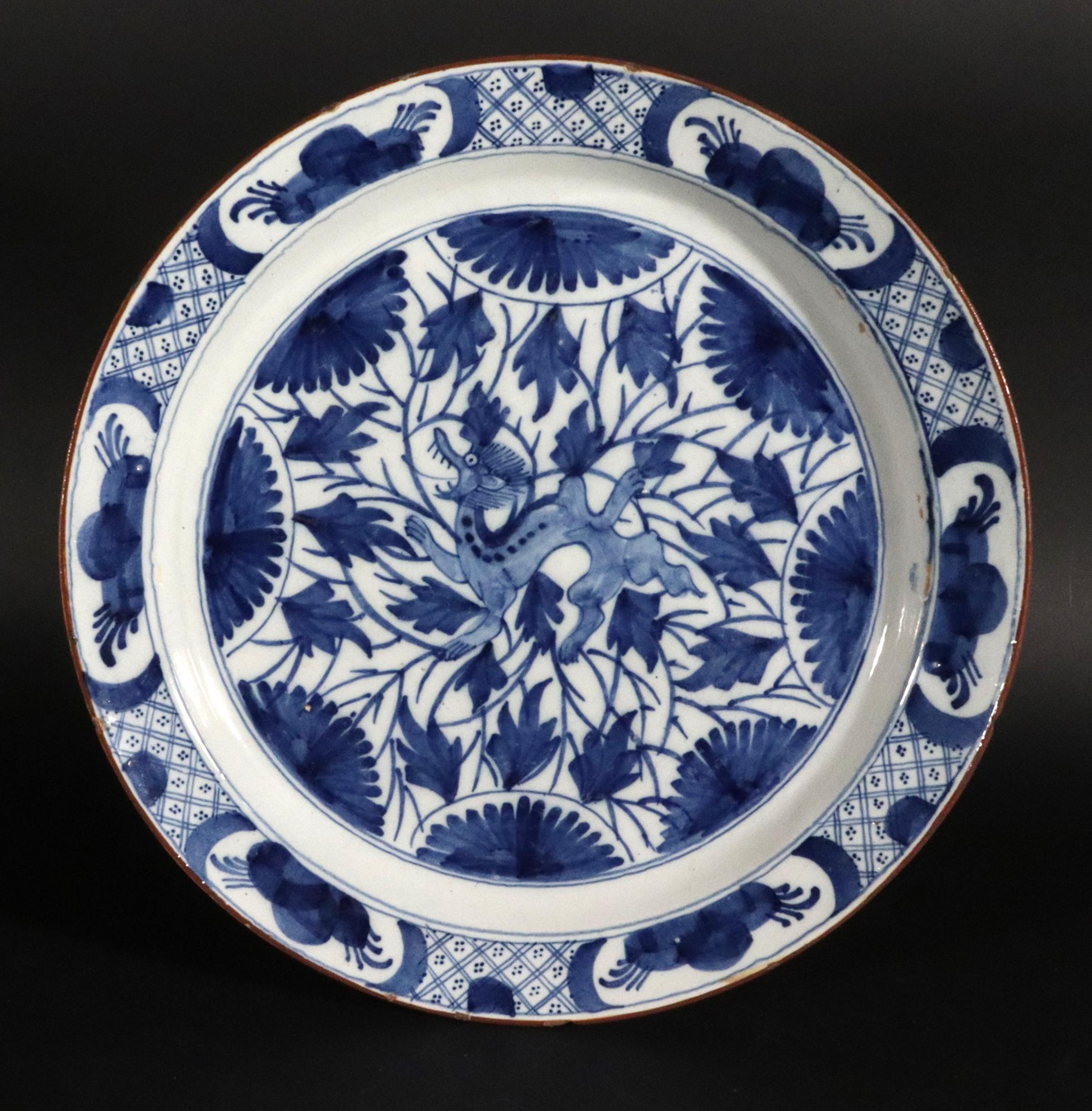 Dutch Delft Large Dish with Chinoiserie Dragon Design,
Circa 1700

The large Dutch Delft dish with a Chinoiserie design after the Kangxi is centered by a dragon amongst stylized flowering branches.  The rim has six reserves with similar stylized