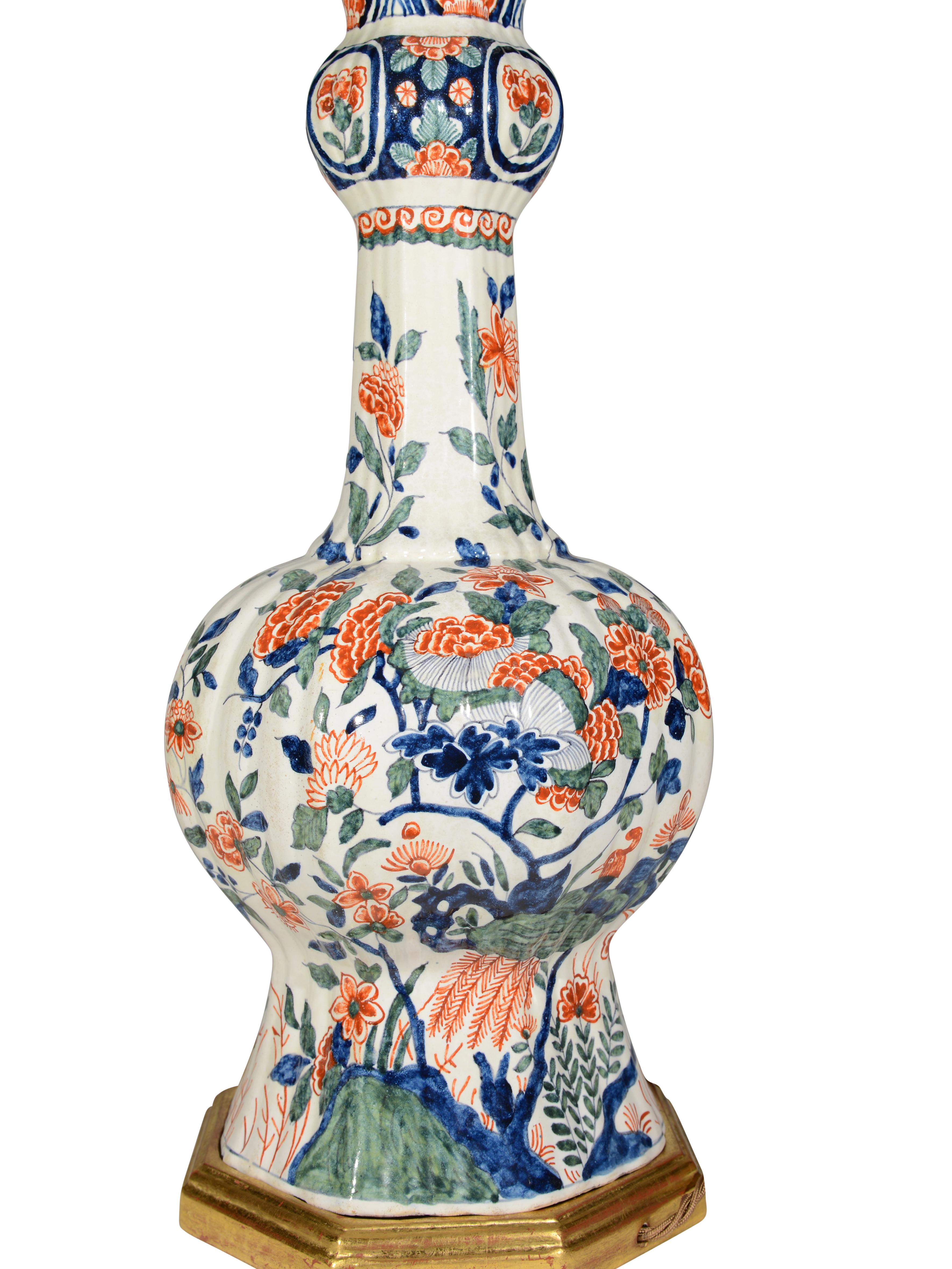 Un grand vase à col d'ail polychrome de la fin du XIXe siècle, de forme hexagonale, décoré d'oiseaux exotiques stylisés, de feuillages fleuris et d'affleurements rocheux en couleurs polychromes sur un fond à prédominance blanche. Ce vase est