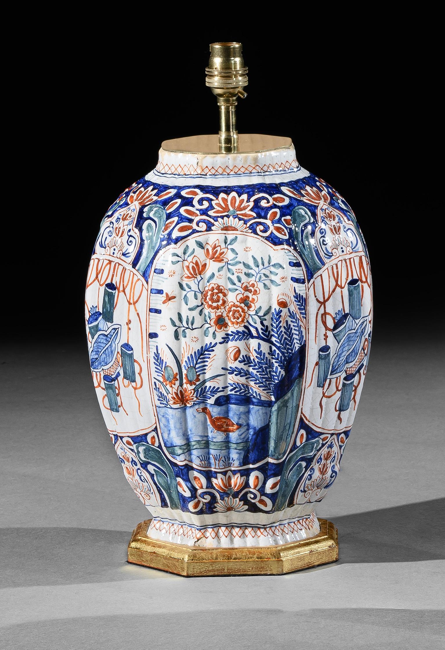 Rare paire de vases anciens Delft polychromes de forme hexagonale, décorés en rouge, bleu et vert sur fond blanc d'oiseaux, de fleurs et d'objets de jardin stylisés. Les lampes sont maintenant montées sur des bases dorées à la main.

Hauteur des