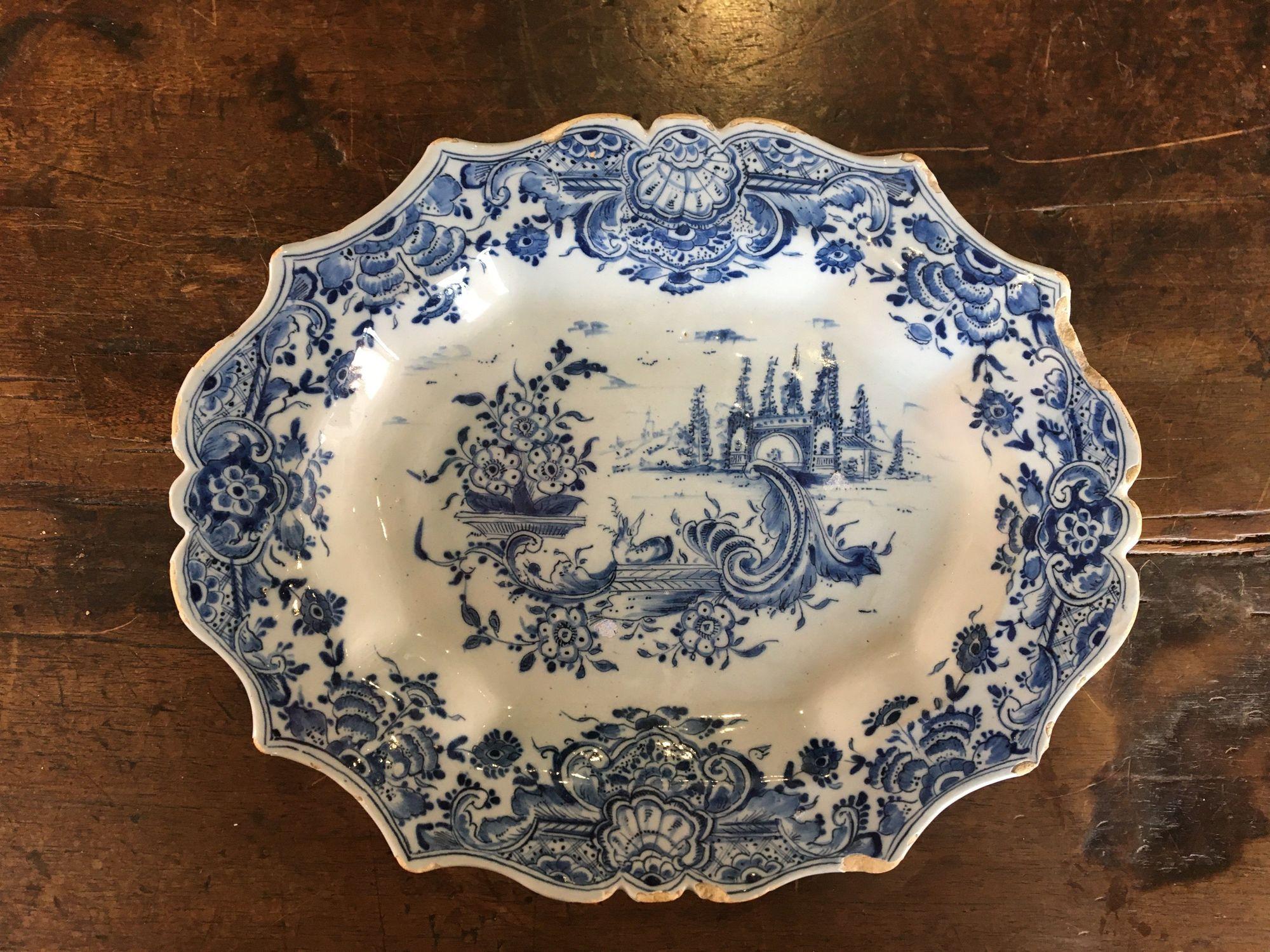 Small Dutch delft oval tray, 18th century, with scalloped rim, floral, landscape and shell decoration, base marked 'IVDH' for Jan van der Hagen of the 'Het Jonge Moriaanshooft' workshop. This delicately formed platter has particularly refined detail