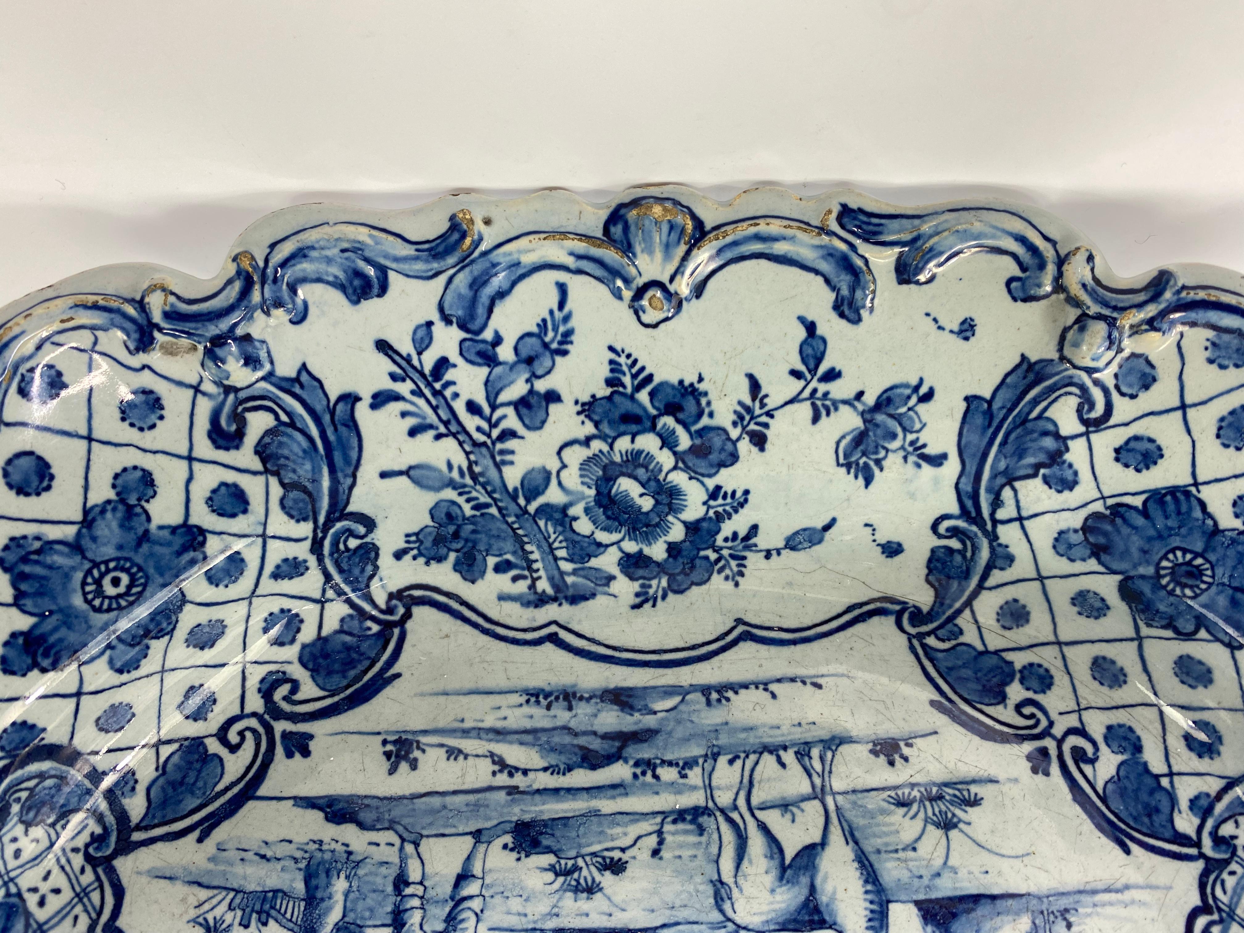 Un raro e grande piatto da portata olandese di Delft di forma rettangolare, fabbrica Van Duyn, 1765 circa. Il piatto profondo, dipinto in blu, presenta una scena europea di un contadino in piedi dietro un cervo, con edifici agricoli sullo sfondo,