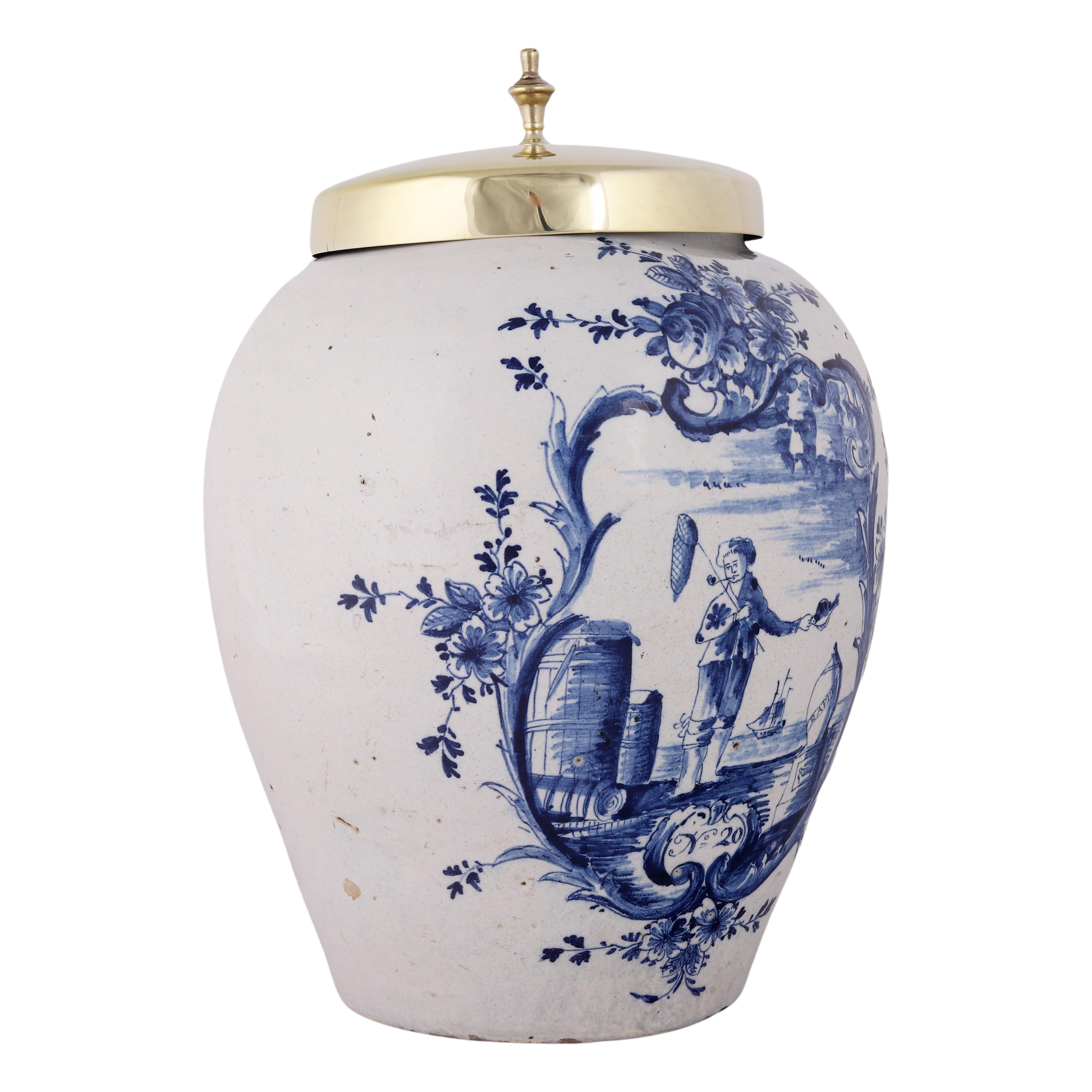 Faïence de Delft
Vers 1740
Atelier : De Vergulde Bloempot (Le pot de fleurs doré)

Rare et très ancien pot à tabac bleu et blanc pour le stockage du tabac à priser avec un couvercle en laiton.
La jarre est décorée d'un pêcheur fumant la pipe, debout